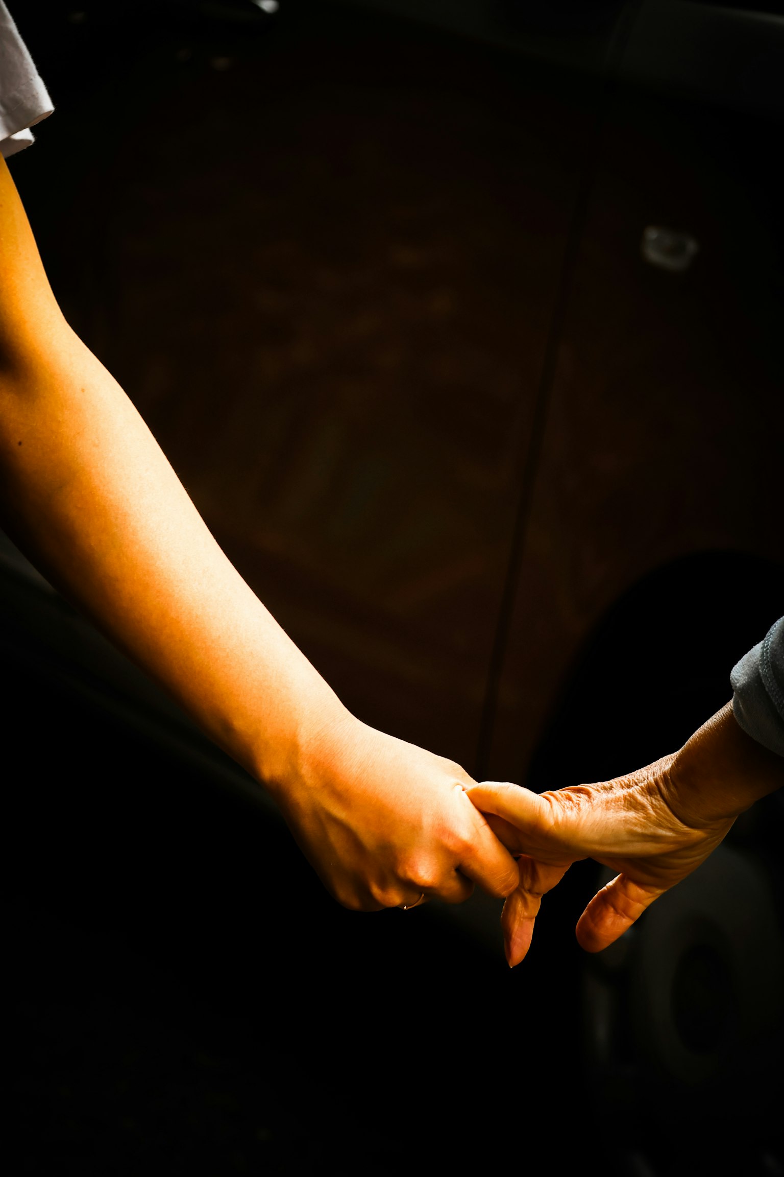 二人の手がつながれているシーン 暗い背景に温かい光が当たる
