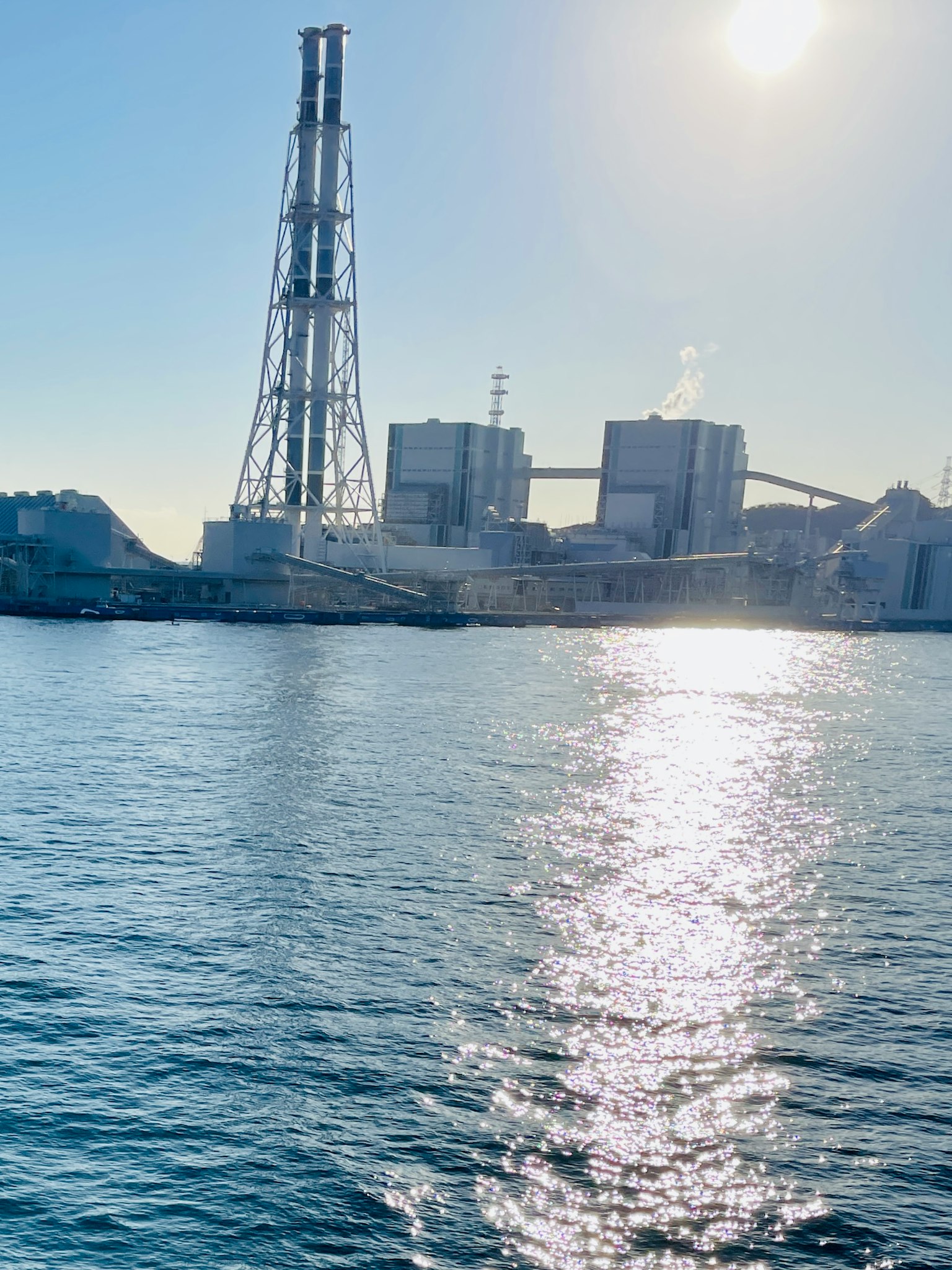 Silhouette d'une usine industrielle reflétée dans l'eau sous la lumière du soleil