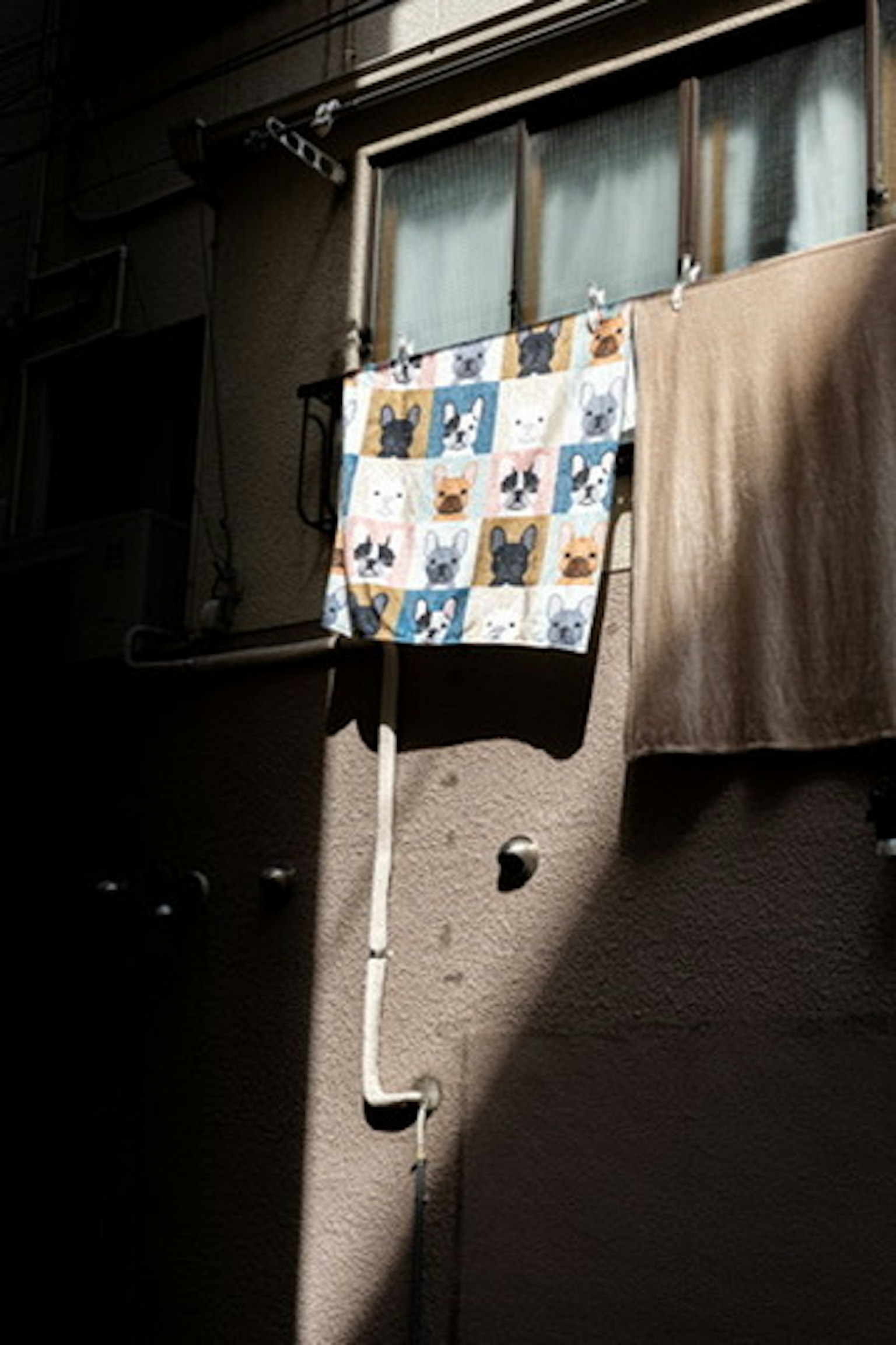 Colorful fabric and brown cloth hanging outside a window