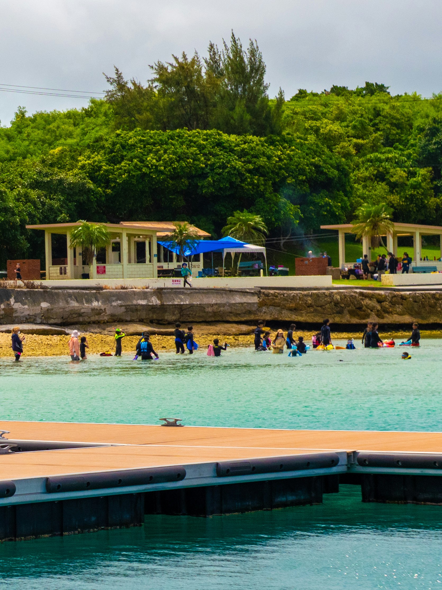 enfants jouant près d’une piscine en bord de mer avec des arbres et un bâtiment