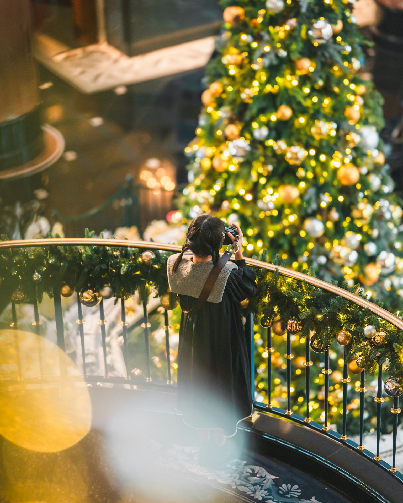 Wanita yang sedang mengambil foto di depan pohon Natal