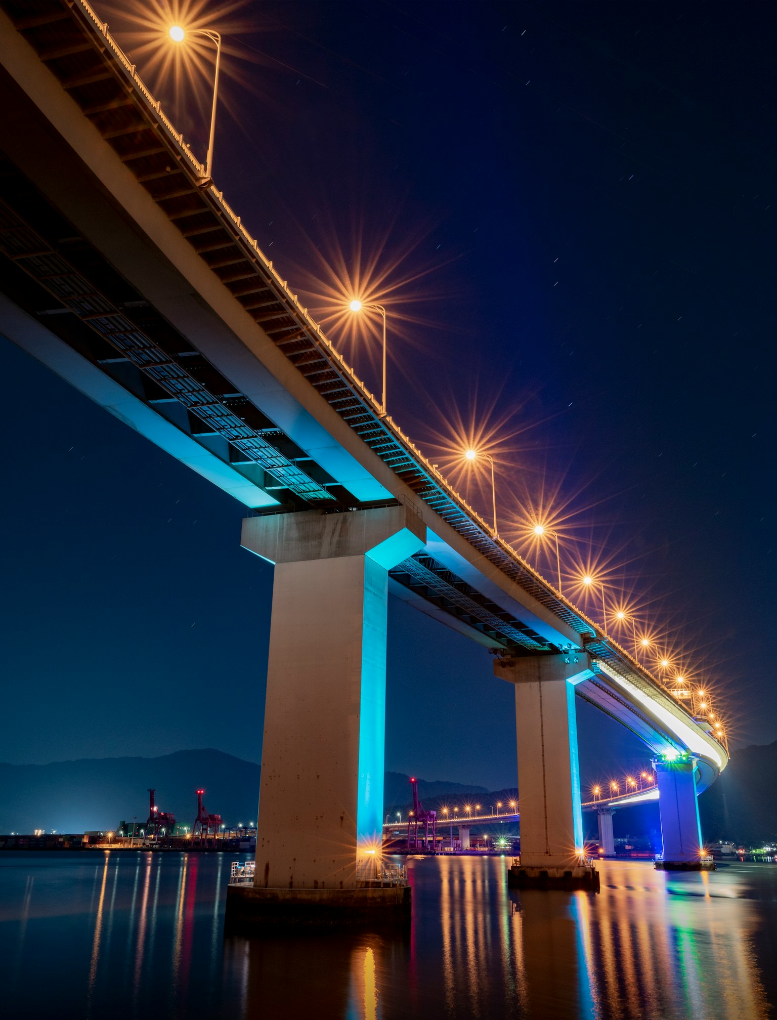 Pemandangan dari bawah jembatan di malam hari Lampu jalan terang di sepanjang struktur