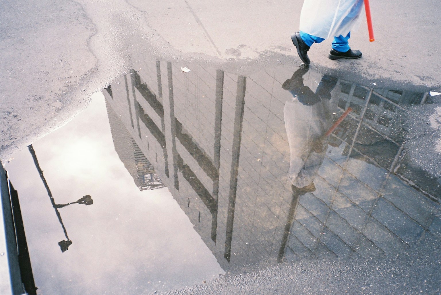 Reflection of a building and a person walking in a puddle