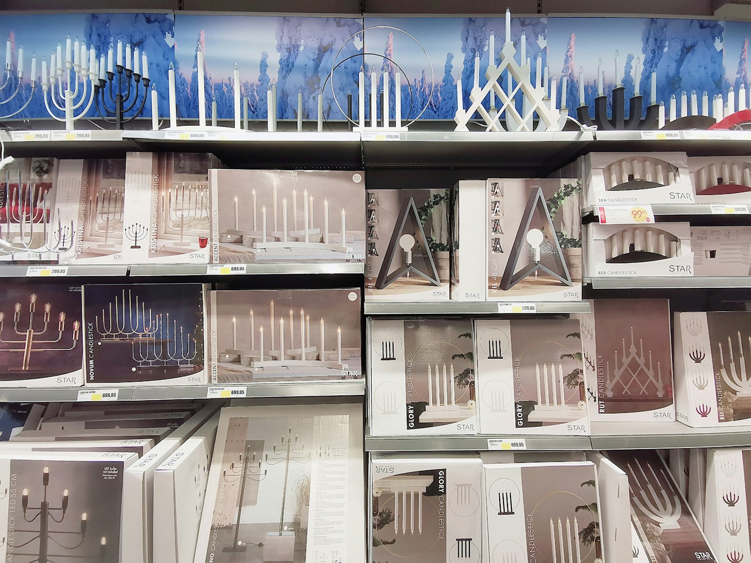 ภาพของชั้นวางที่แสดงที่ใส่เทียนสีขาวและเบจพื้นหลังมีลวดลายสีน้ำเงิน