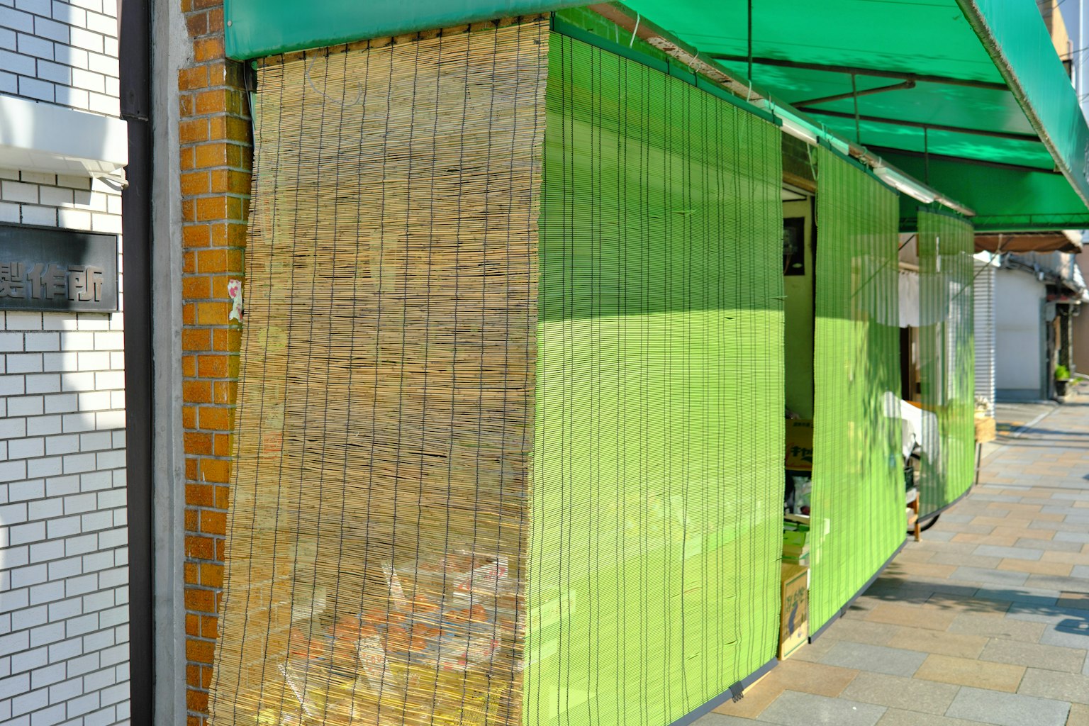 Esterno di un negozio con un muro verde e una tenda di bambù