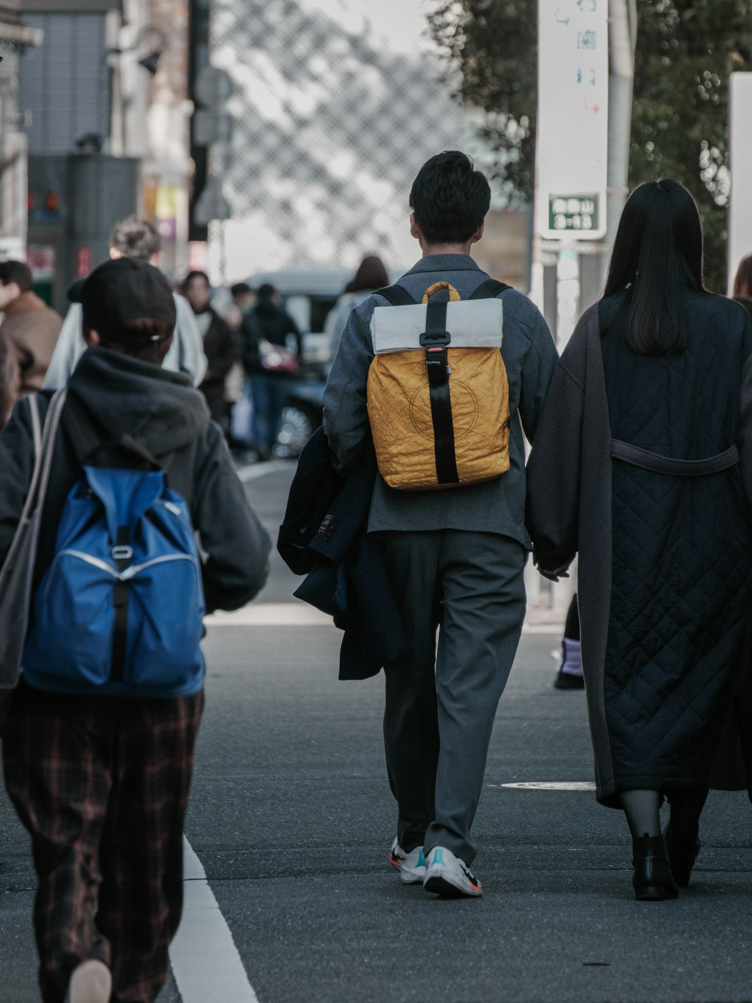 People walking on the street a man with a yellow backpack