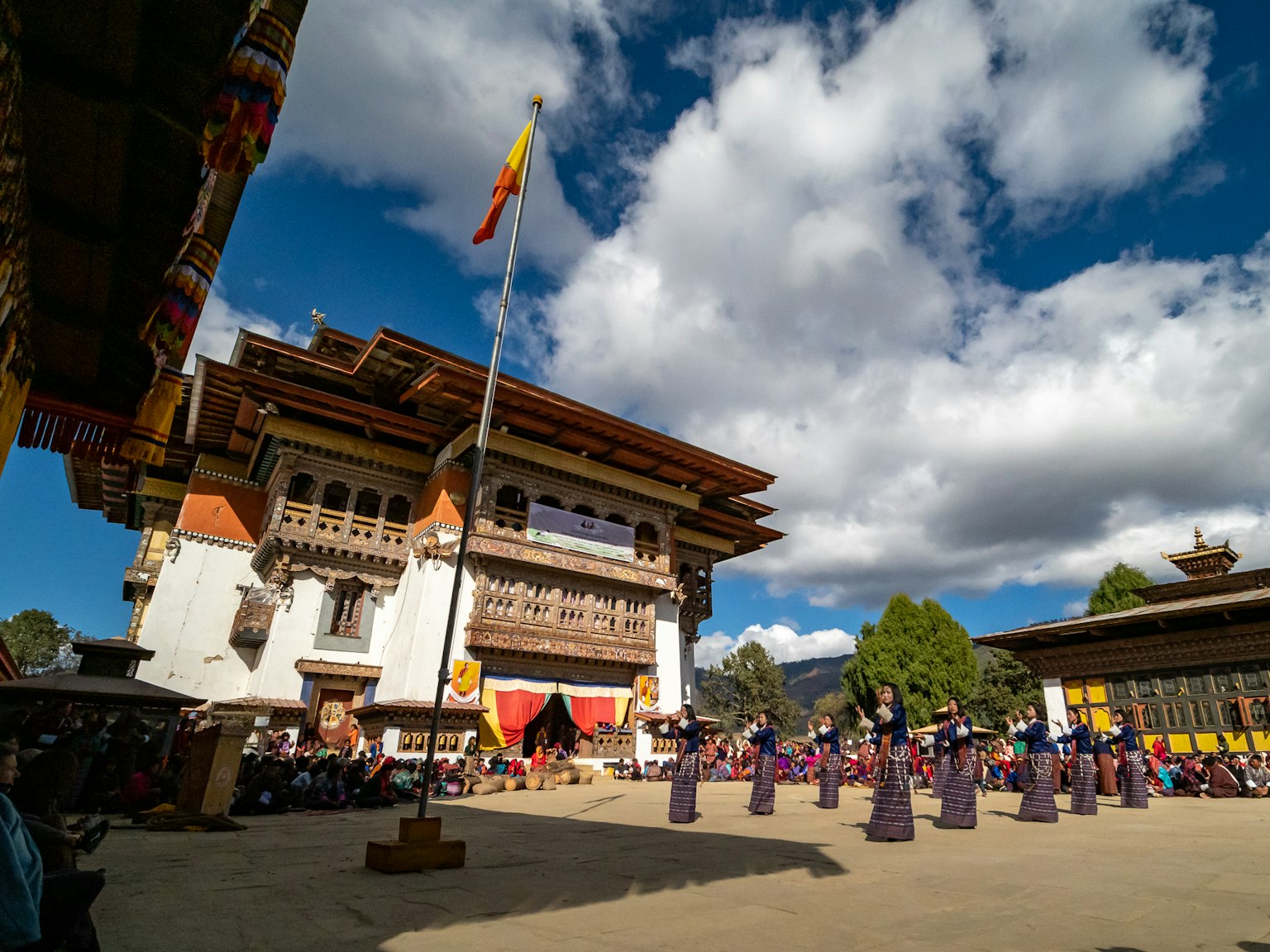 Scena di festival tradizionale bhutanese sotto un bellissimo cielo azzurro con danzatori e edifici storici