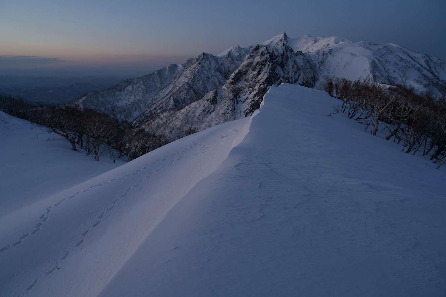 Cordillera cubierta de nieve bajo un cielo crepuscular