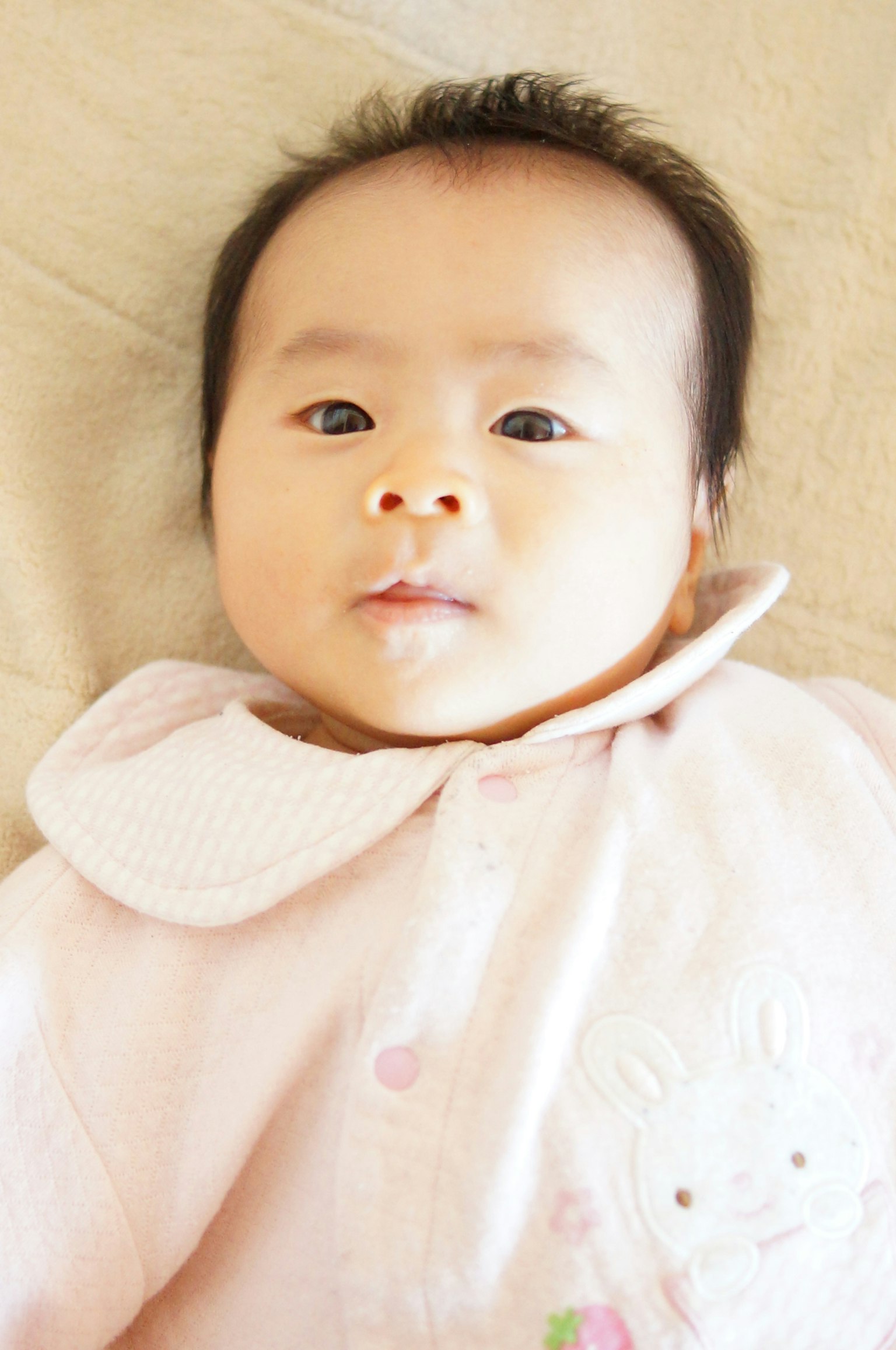 Baby wearing a pink outfit with a calm expression looking at the camera