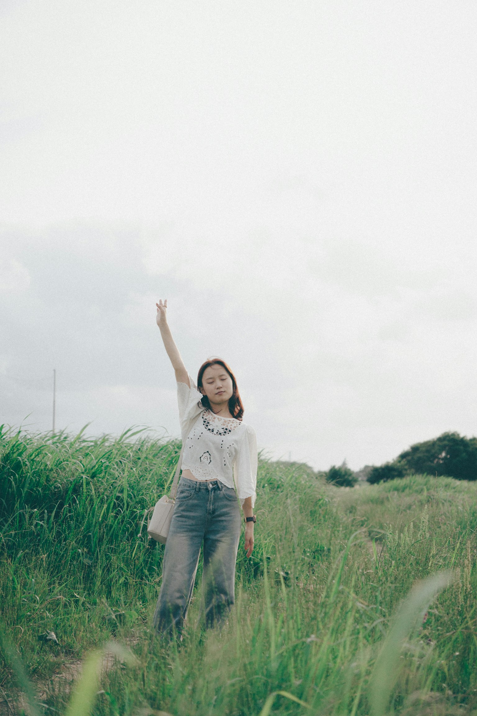 Một người phụ nữ giơ tay trong cánh đồng cỏ