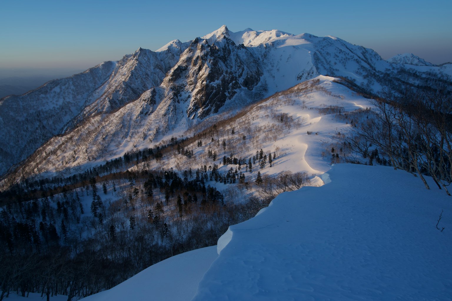 Snow-covered mountain range with a clear blue sky