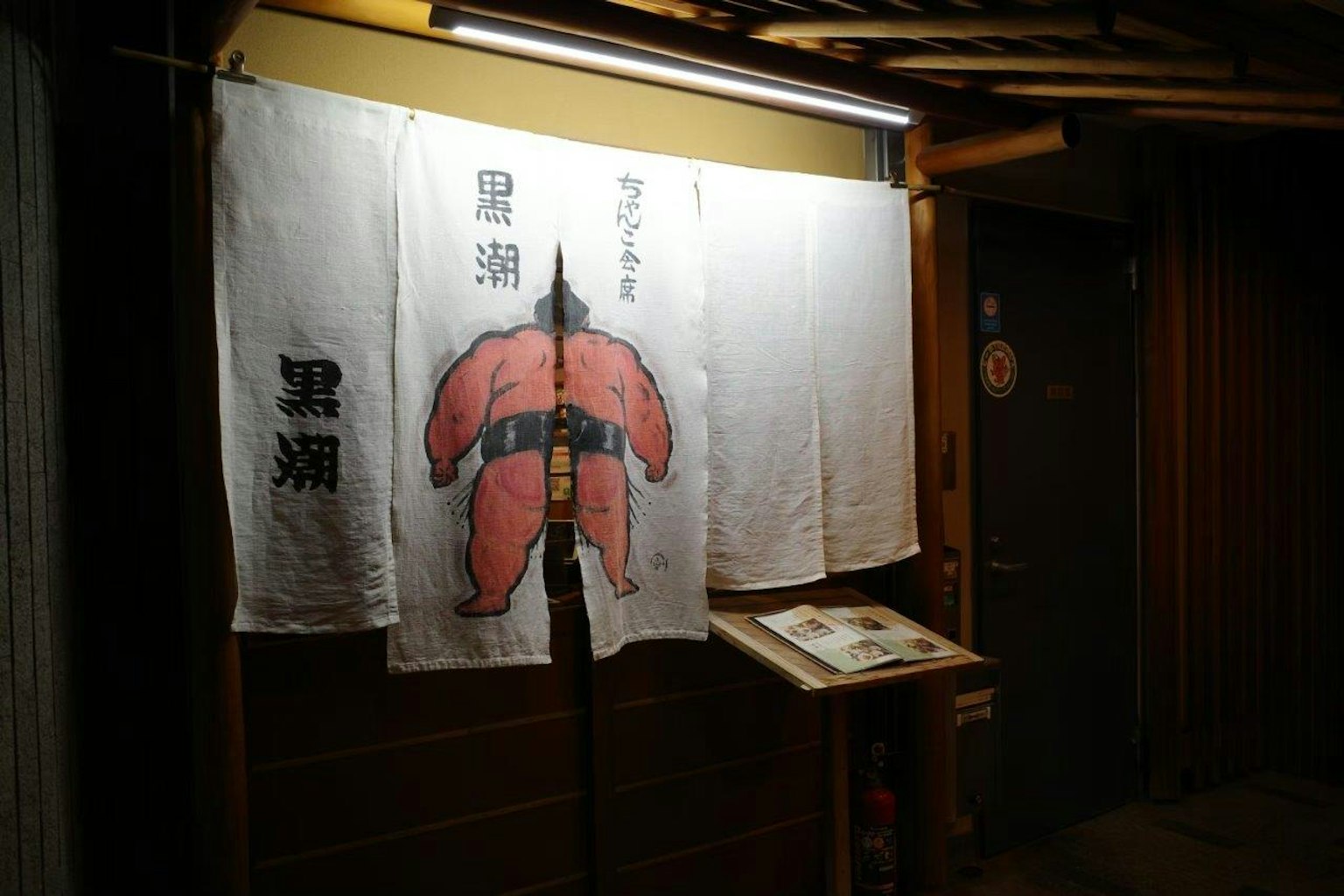 Pintu restoran Jepang dengan tirai noren bergambar sumo merah