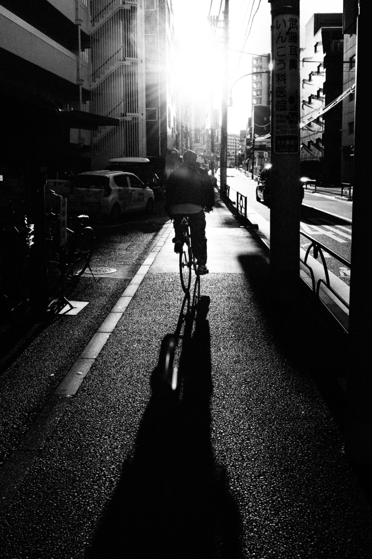 Silhouette d'une personne à vélo sur une rue de la ville avec la lumière du soleil venant de derrière