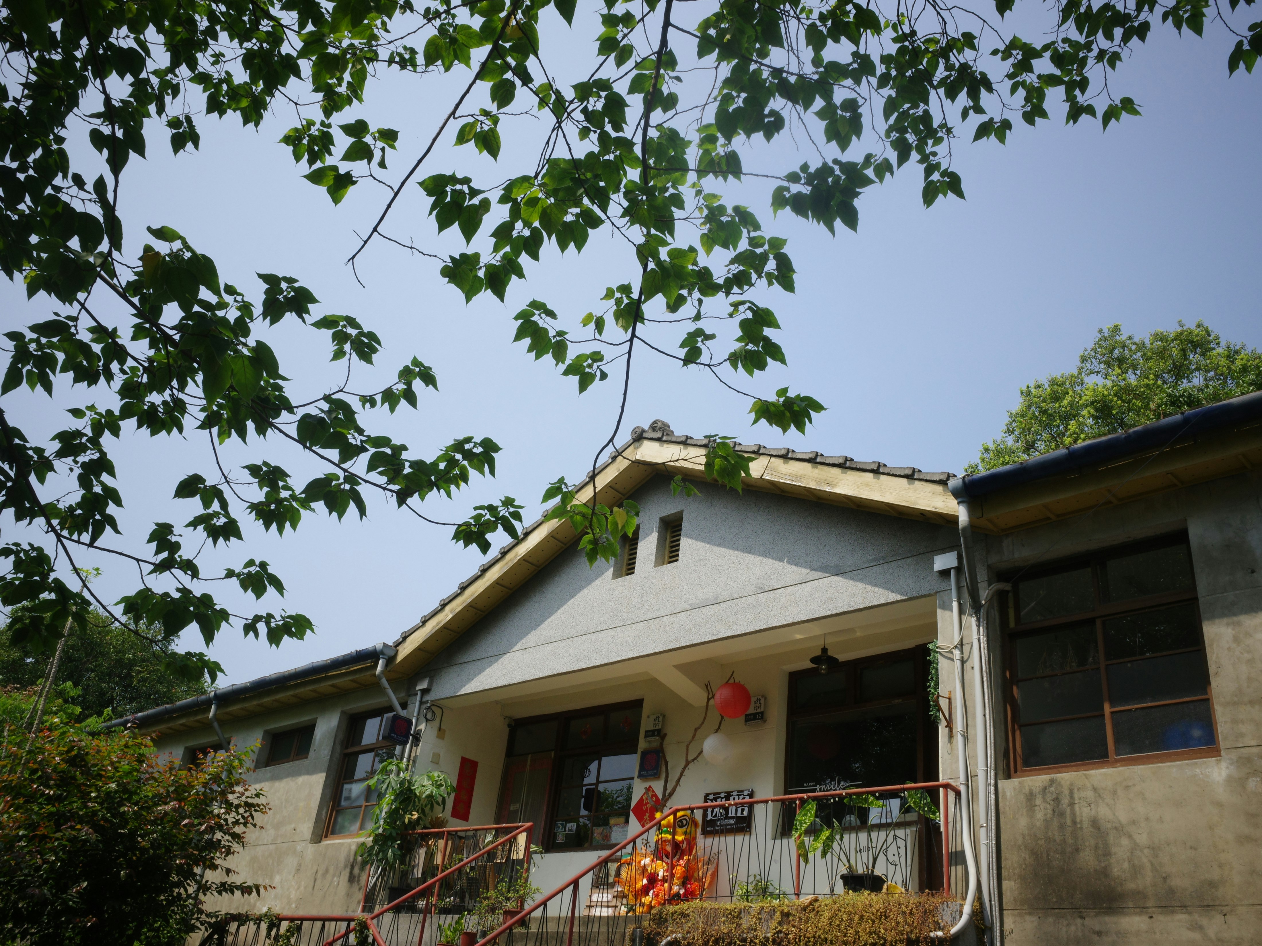 Eingang und Balkon eines alten Hauses, durch Baumzweige gesehen