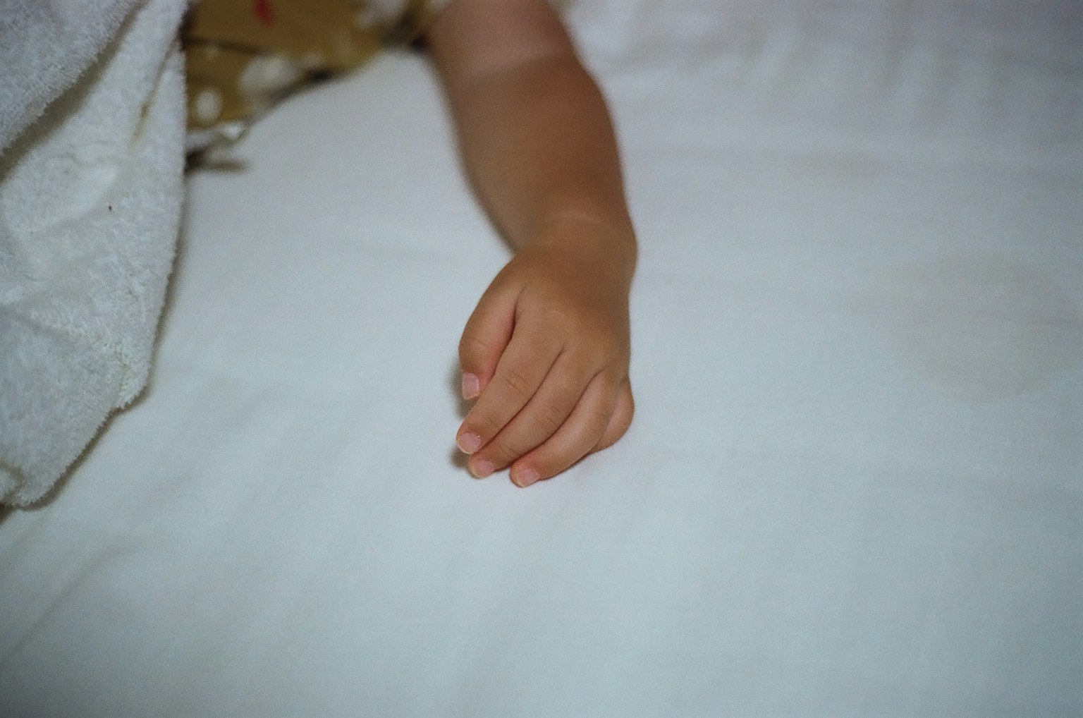 Tangan anak yang terletak di atas seprai putih
