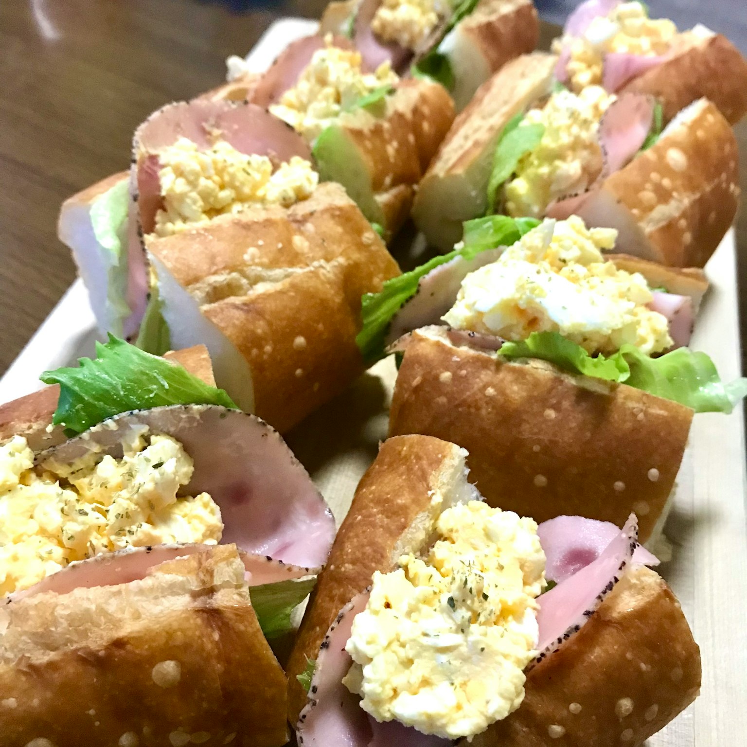 Assortimento di panini ai pretzel farciti con prosciutto, lattuga e insalata d'uova