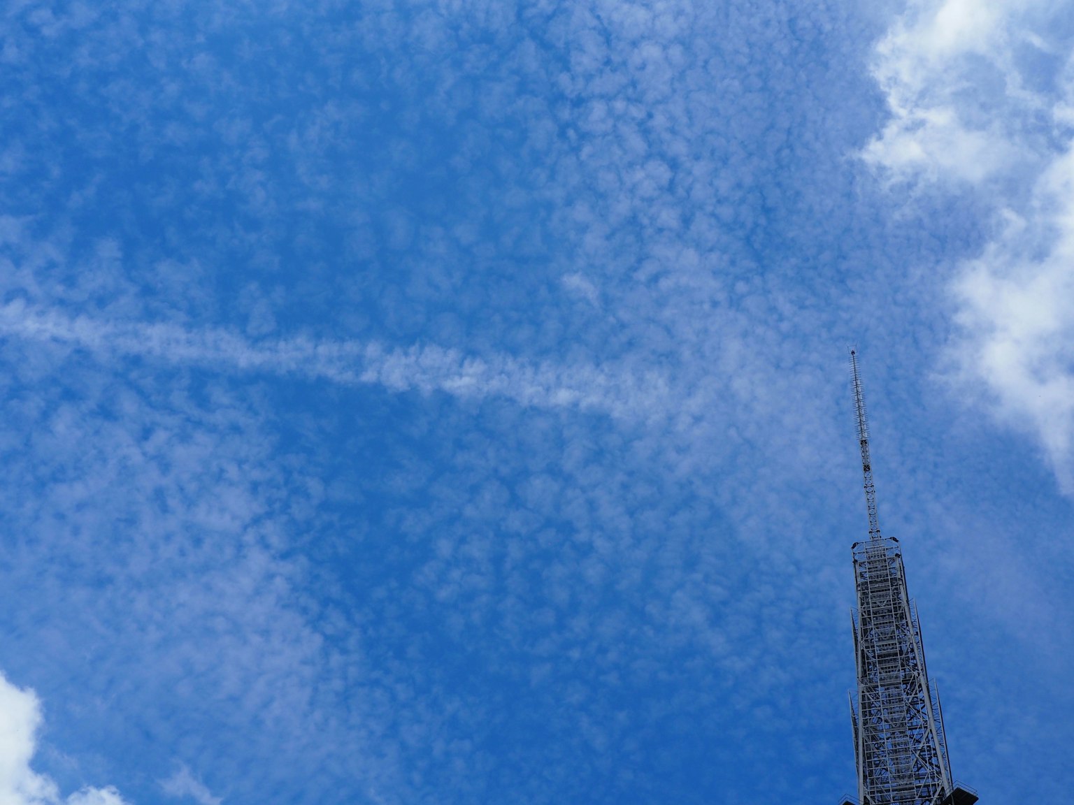 Immagine di una torre alta contro un cielo blu pieno di nuvole