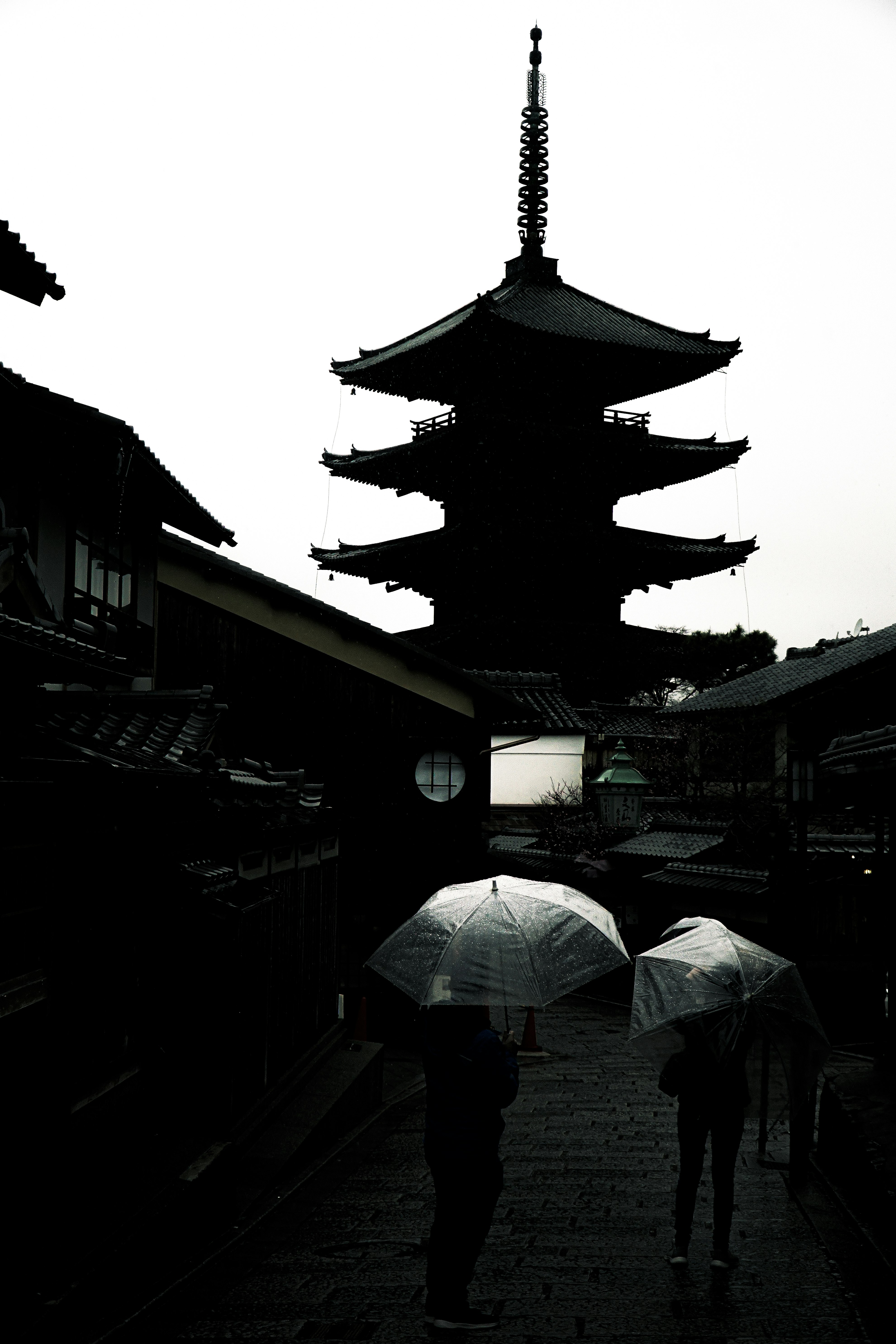 雨傘をさした人と五重塔のある寺院の参道