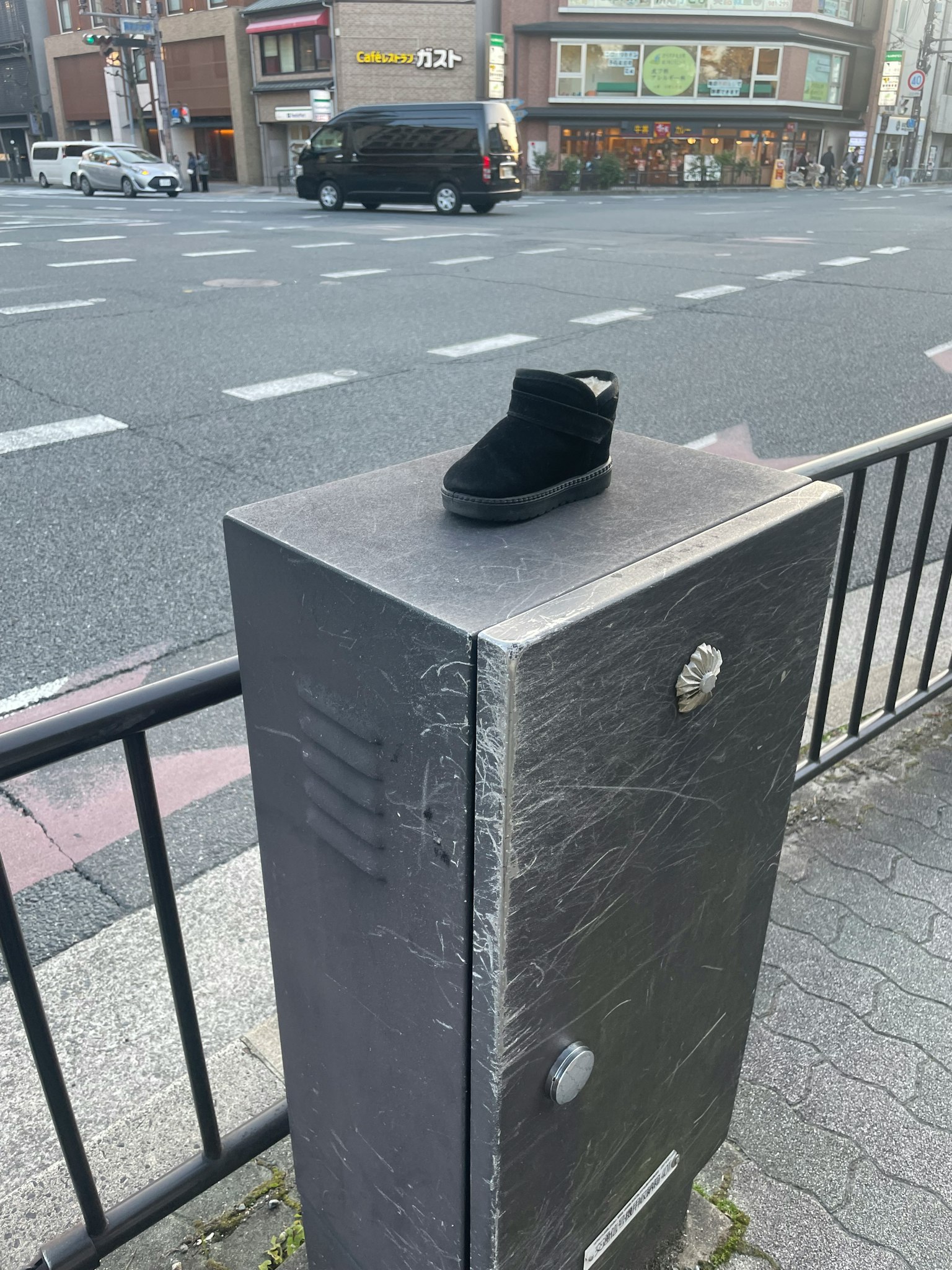 Une chaussure noire posée sur une boîte utilitaire de rue