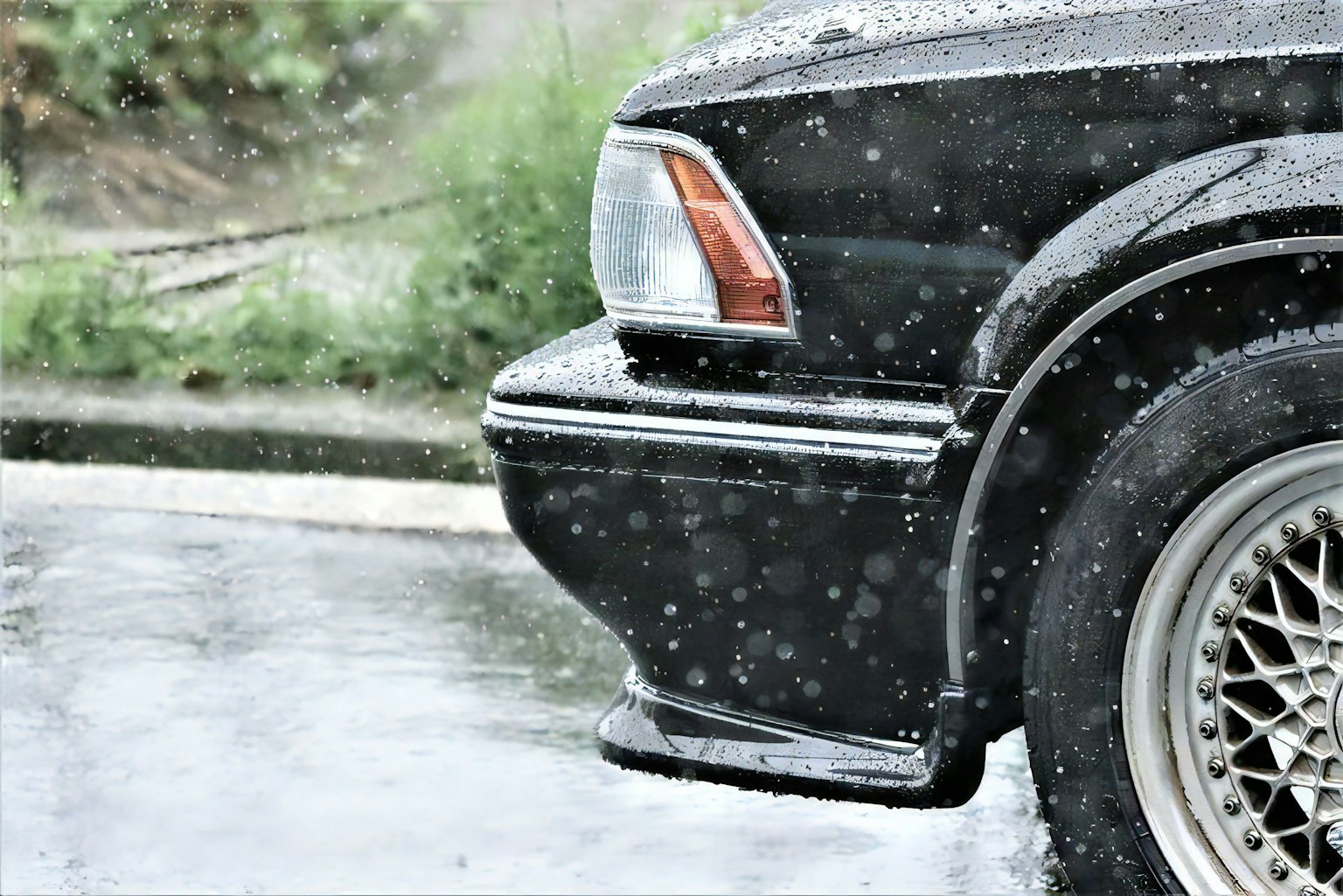 Black car rear bumper and wheel in the rain