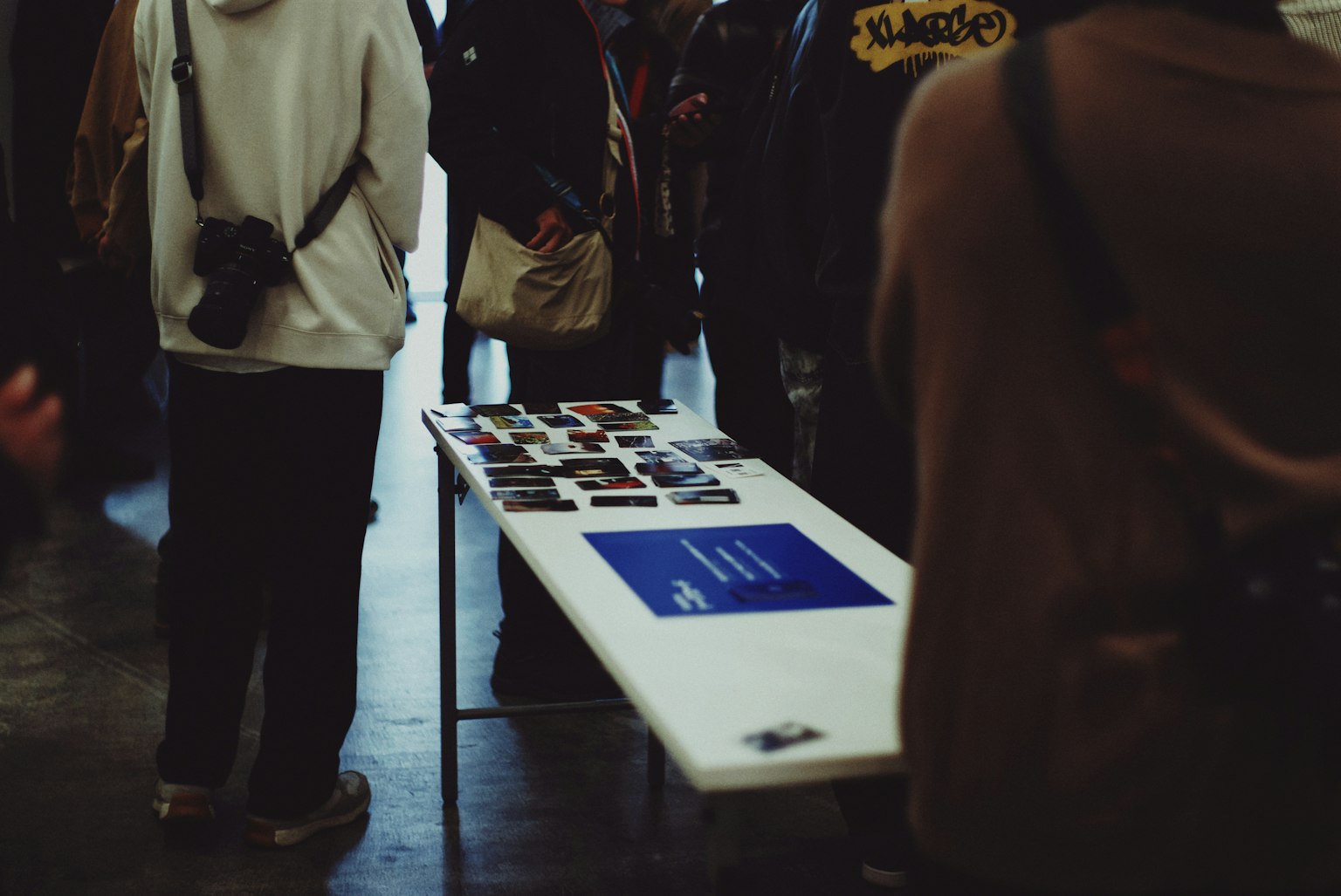 People gathered around a table displaying photographs and materials at an event