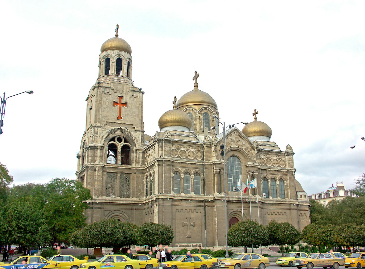 Grand cathedral exterior with golden domes and cross surrounded by taxis