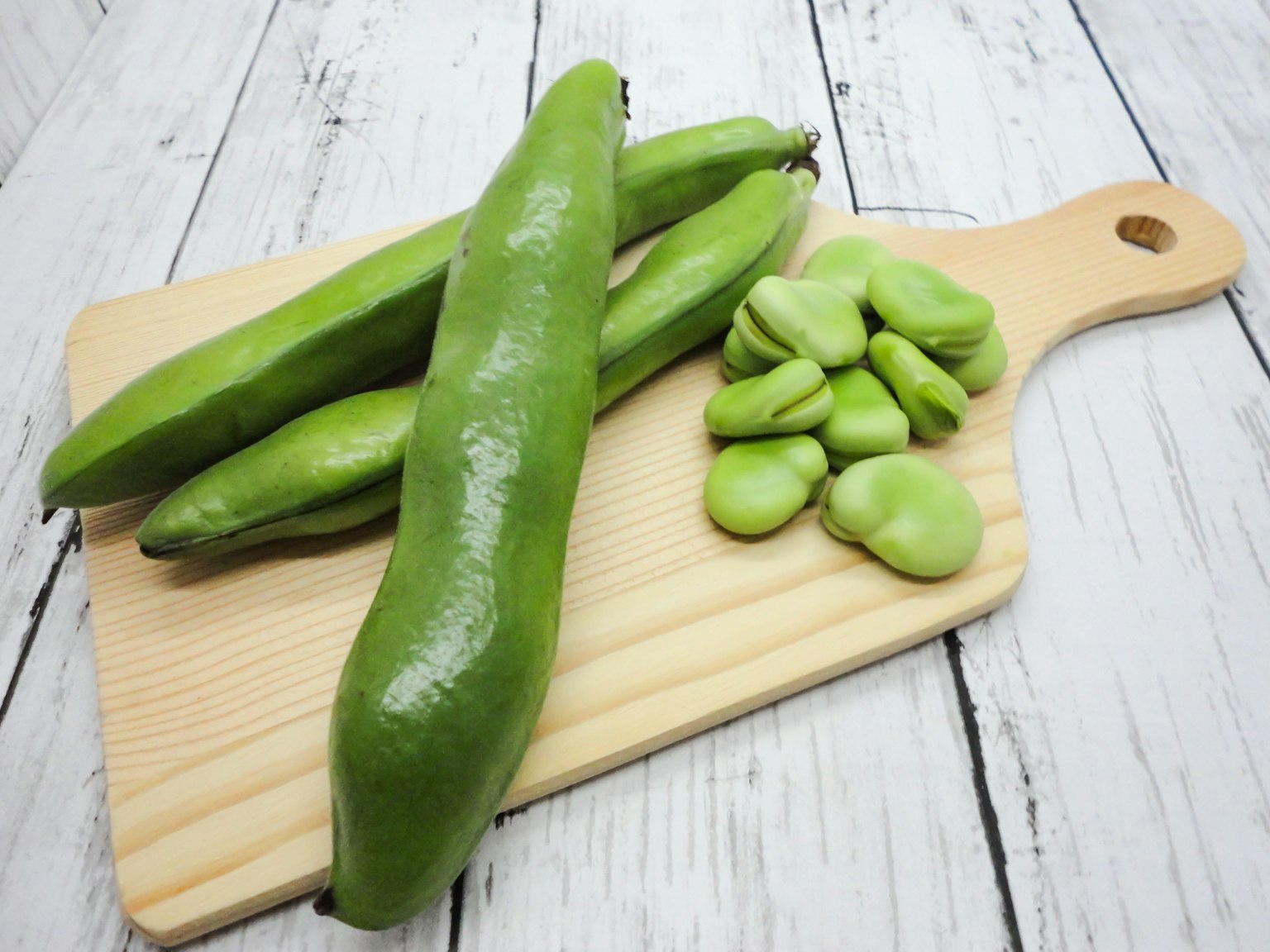 Fagioli verdi e grandi baccelli su un tagliere di legno