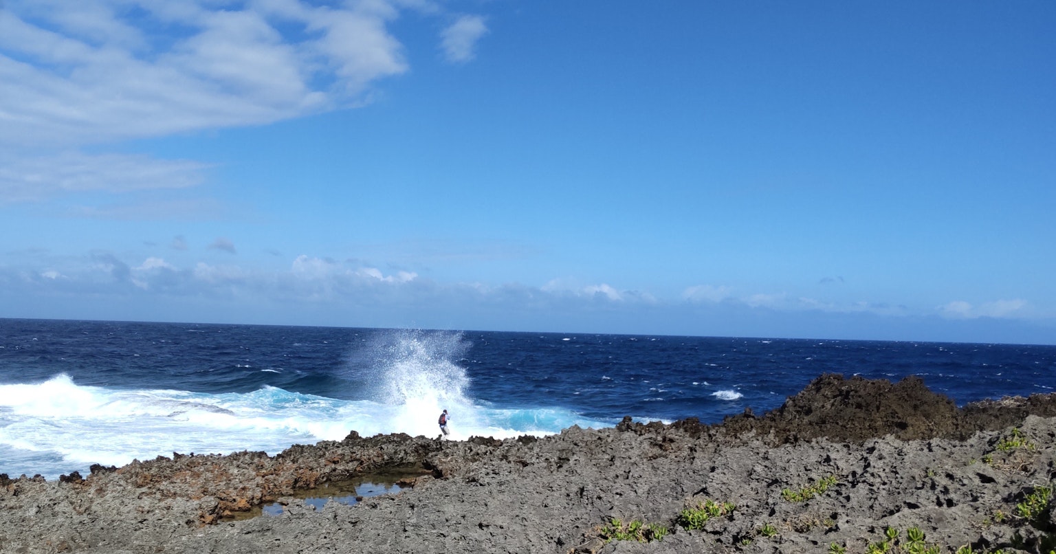 Paysage côtier avec ciel bleu et vagues s'écrasant sur le rivage rocheux