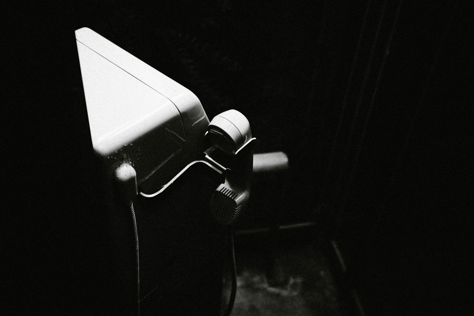 Coin d'une cuvette de toilette blanche illuminé sur un fond sombre