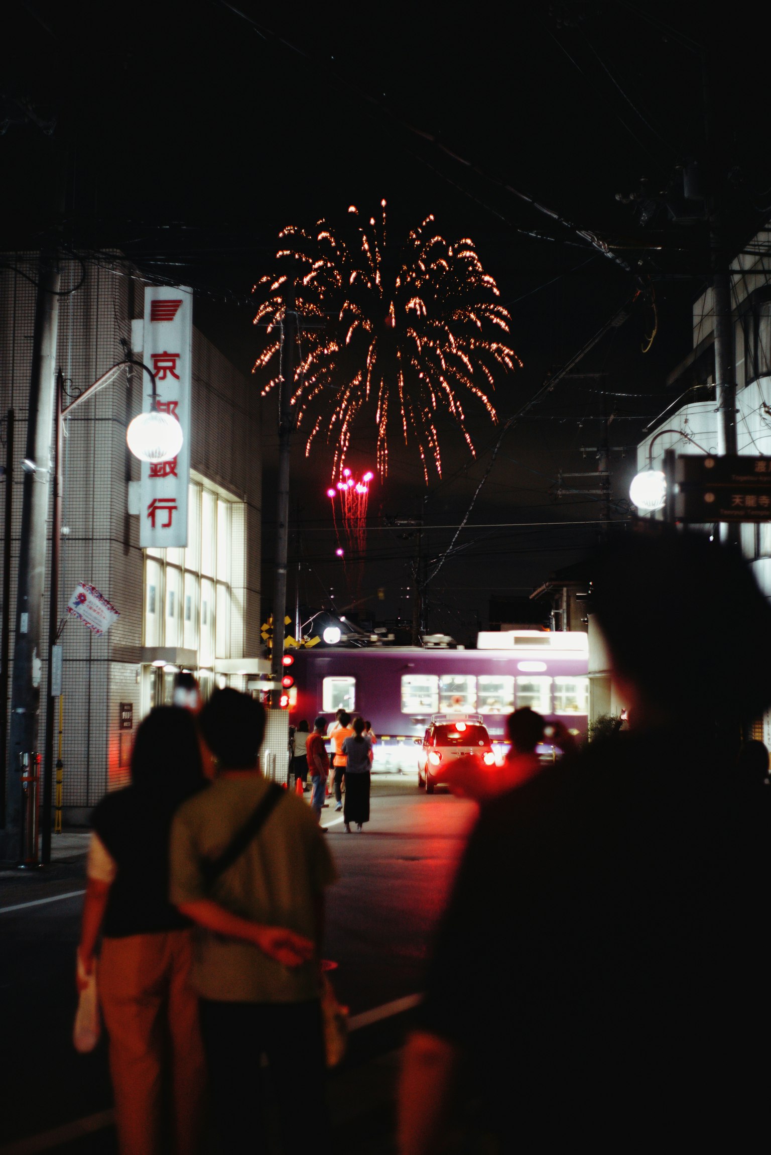 夜空に花火が打ち上げられ人々が楽しむ街の風景