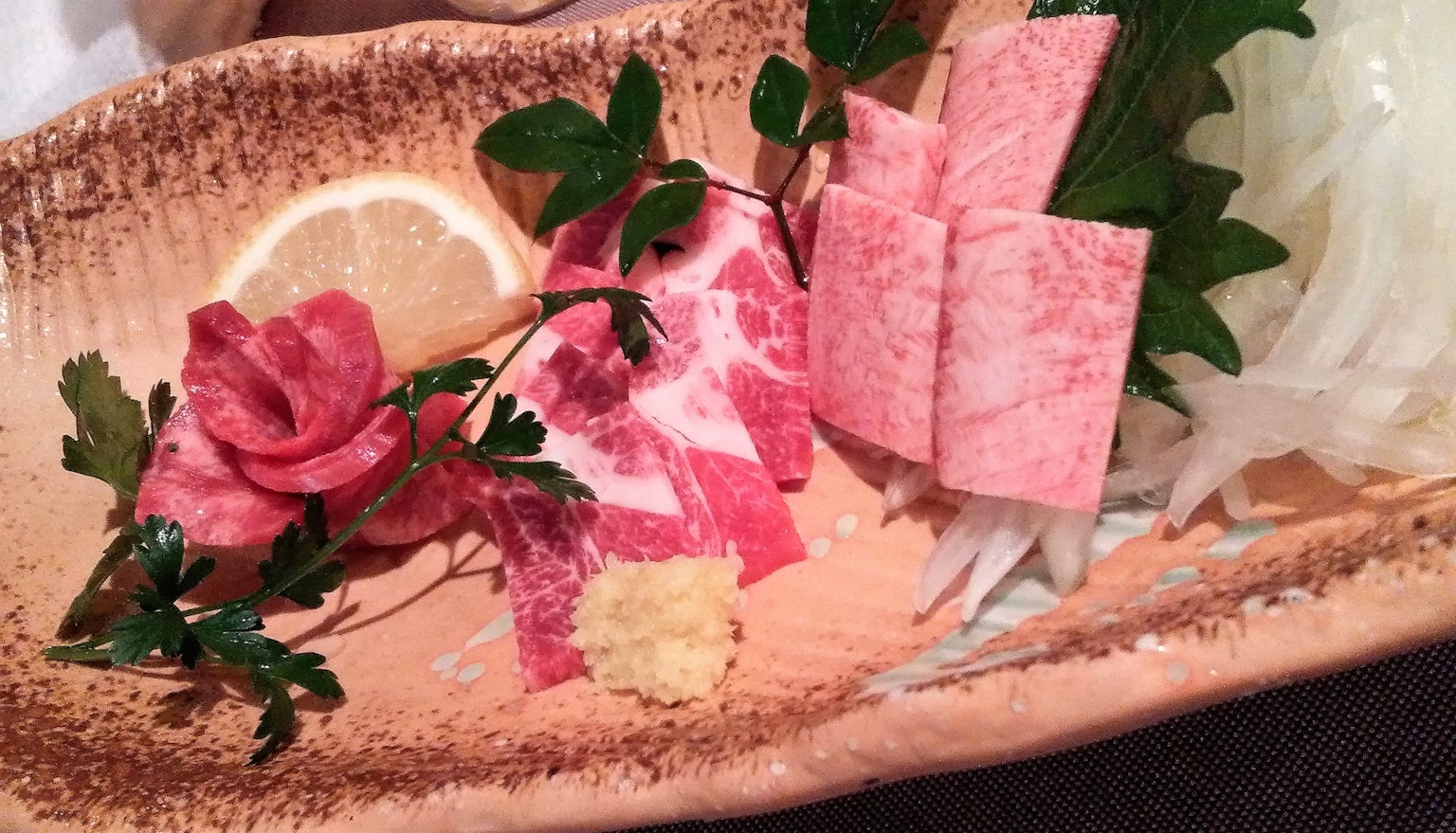 Sashimi tranché avec citron et persil sur une assiette