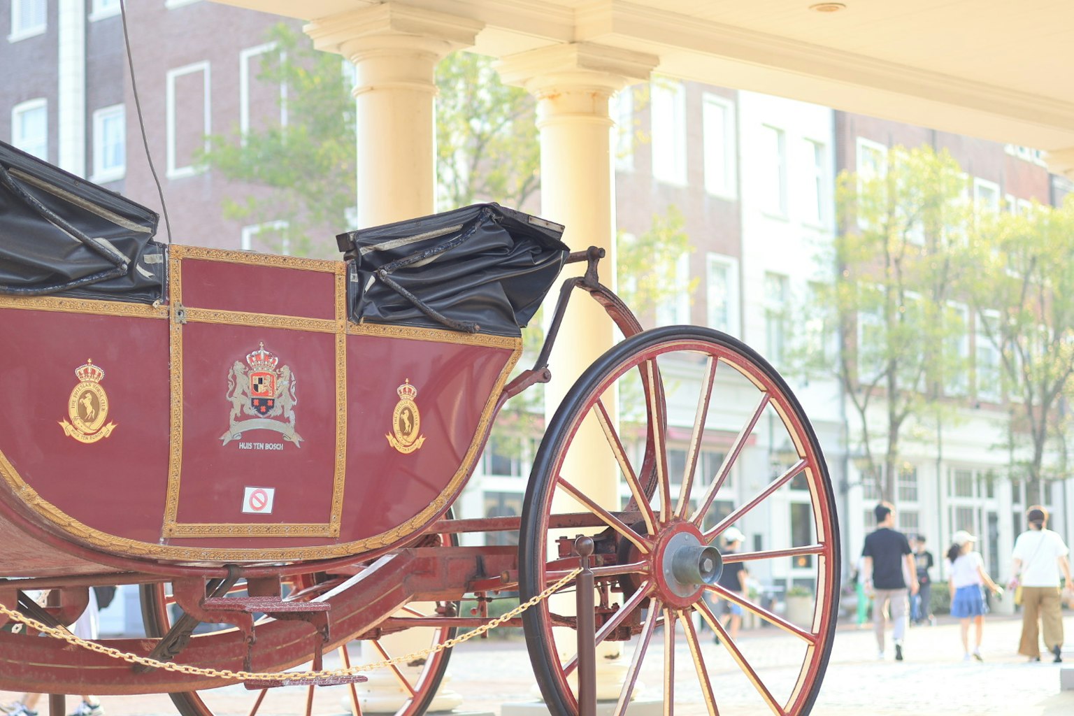 Carrozza rossa vicino a edifici con persone che camminano