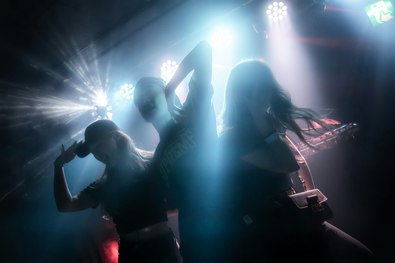 Siluetas de mujeres actuando en el escenario con iluminación colorida y niebla