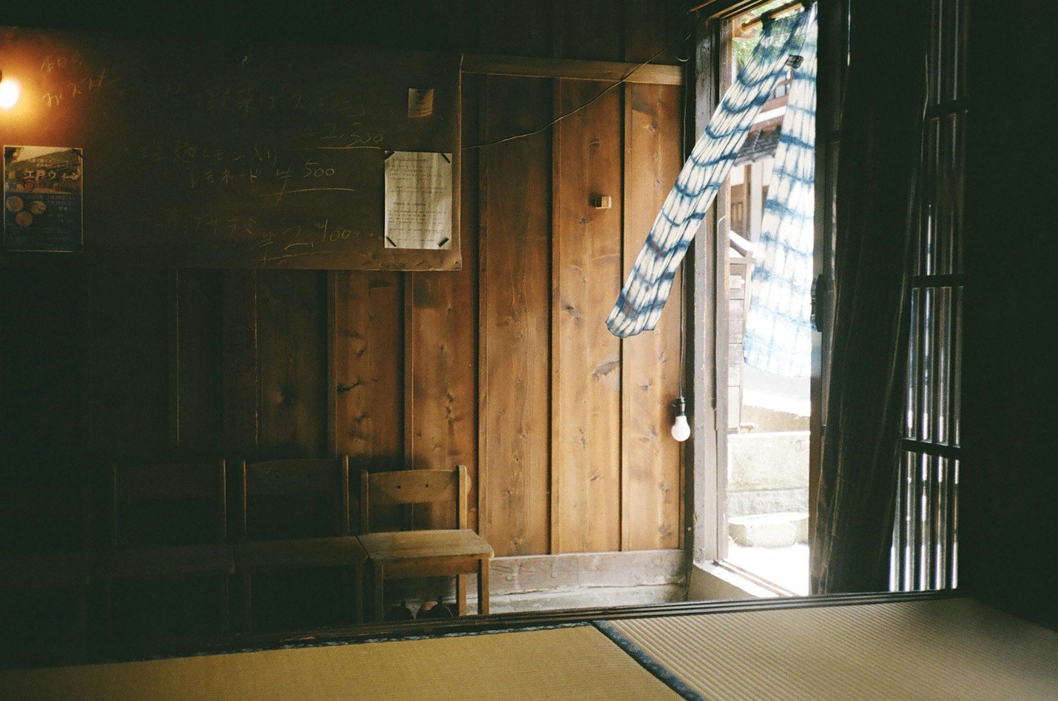 Stanza giapponese tradizionale con pareti in legno e tatami Abbigliamento che fluttua nel vento alla porta aperta