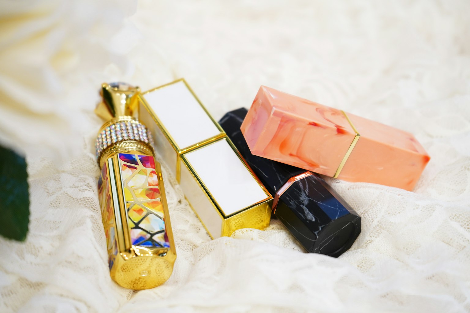 Bouteilles de parfum colorées et rouges à lèvres disposés sur une surface en fourrure blanche