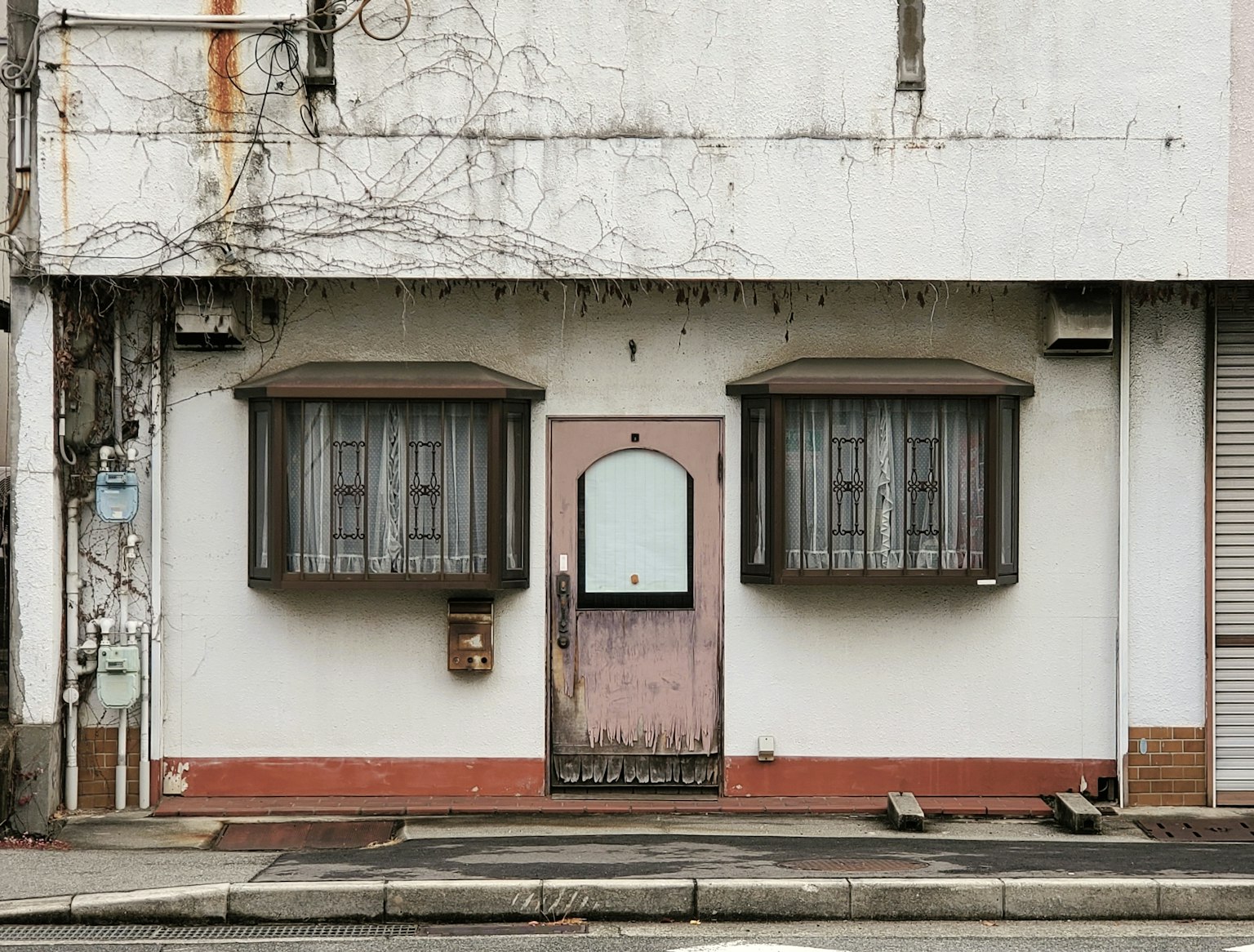 Fachada de un edificio antiguo con dos ventanas y una puerta central