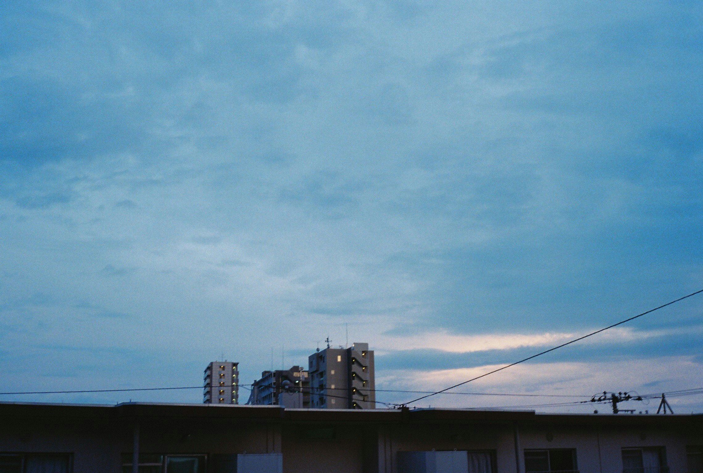 夕暮れの空と住宅街の屋根、電線が走る風景