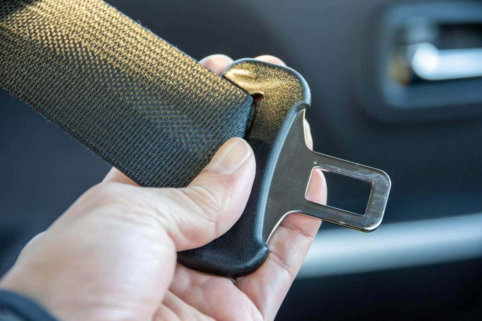 Gros plan sur une main tenant une ceinture de sécurité de voiture