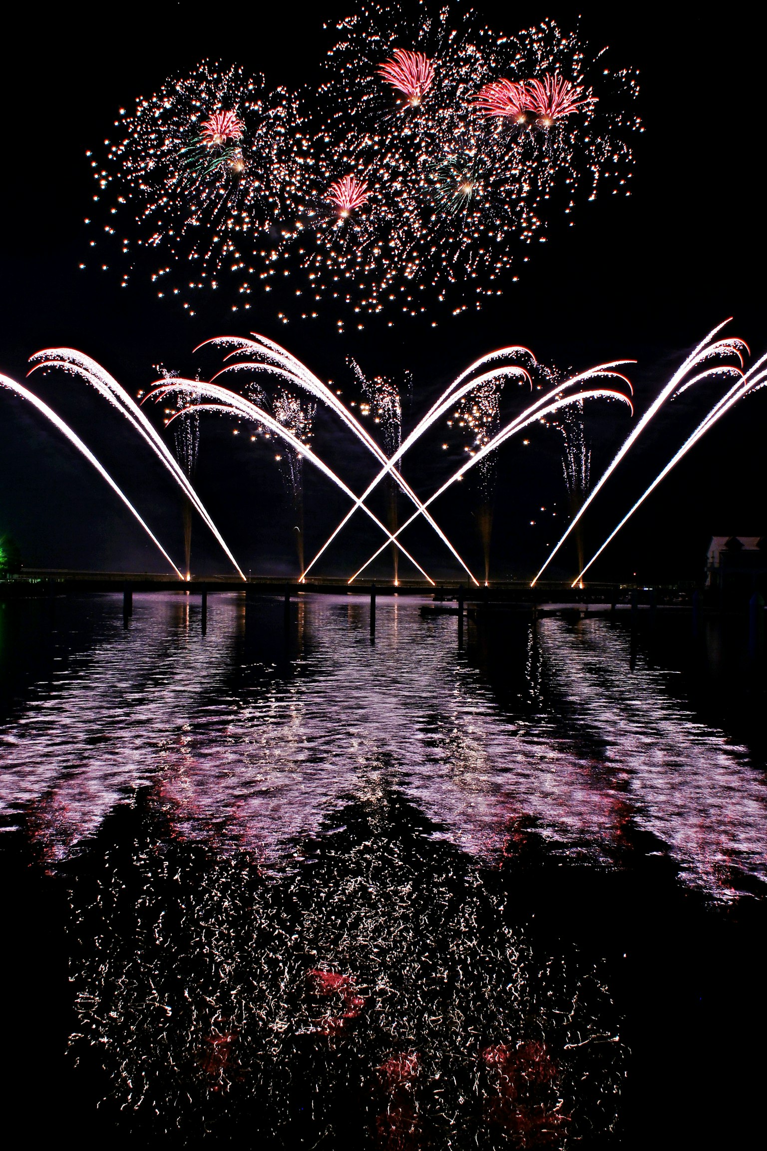 夜空に広がる花火と水面に映る色とりどりの光