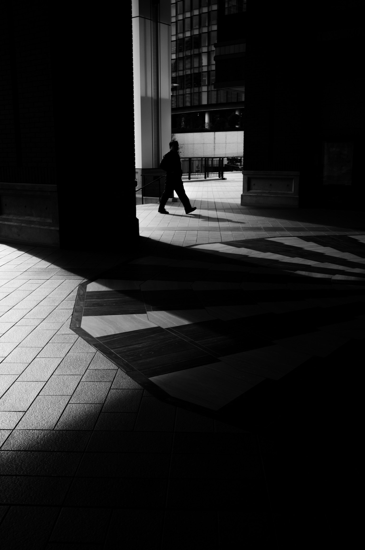 Scena urbana in bianco e nero con una persona che cammina nell'ombra