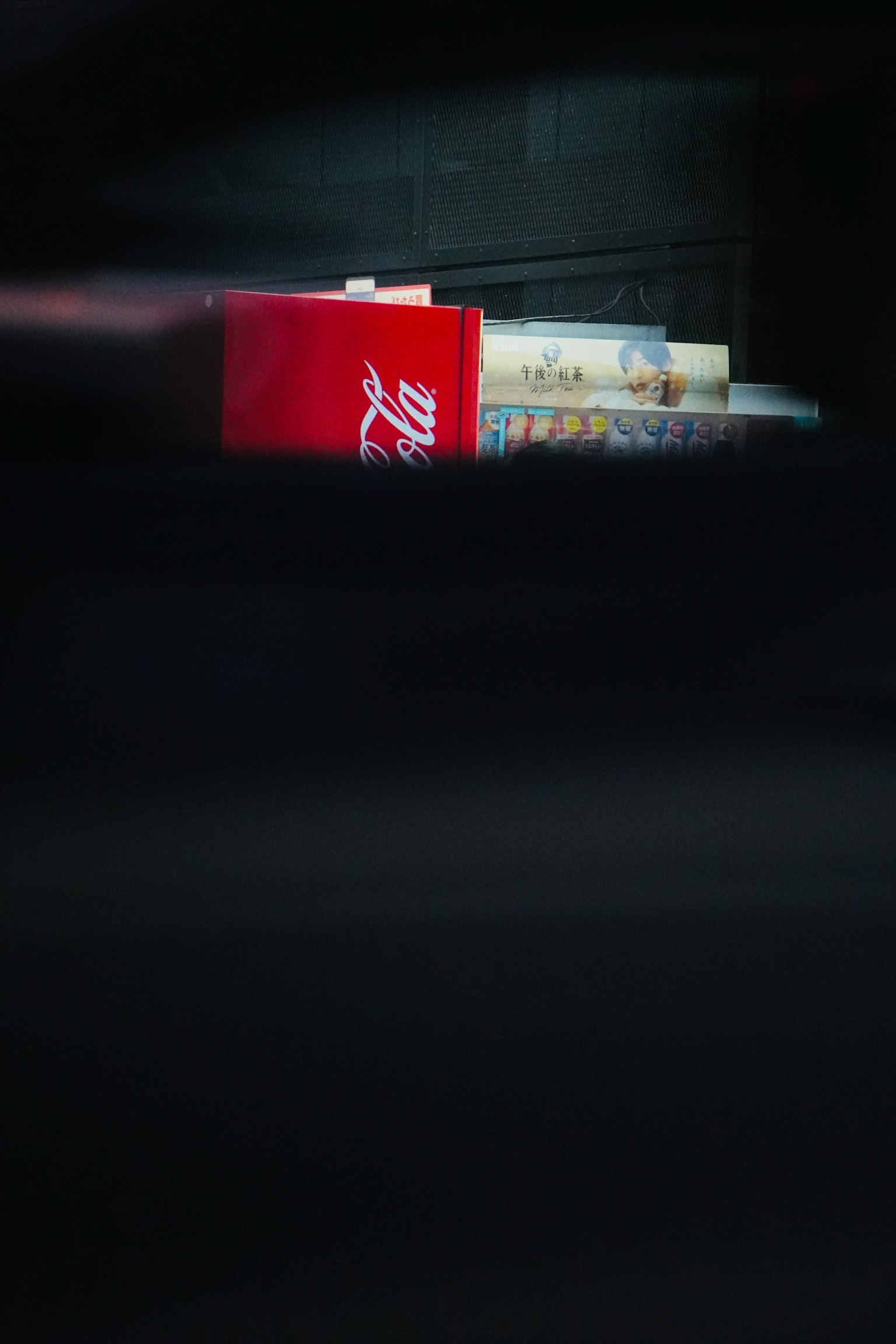 A red Coca-Cola box and books partially visible against a dark background