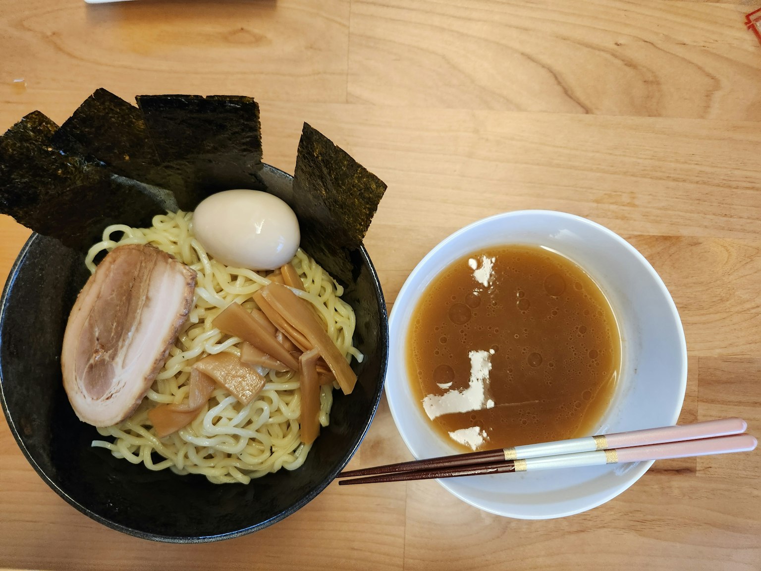 Sekumpulan ramen dengan saus celup berisi daging babi iris telur dan nori di samping