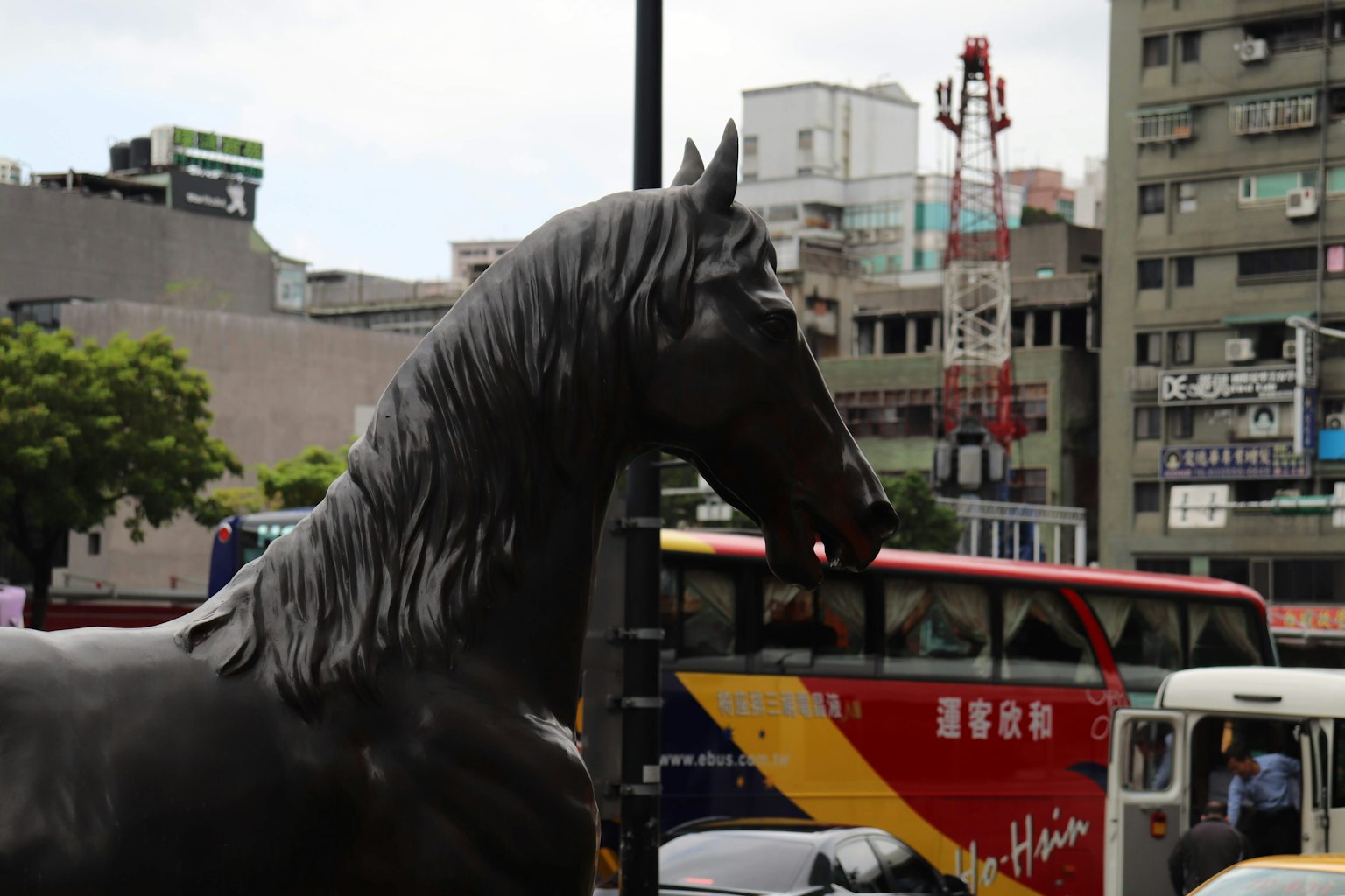 Une sculpture de cheval dans la ville avec des bus en arrière-plan