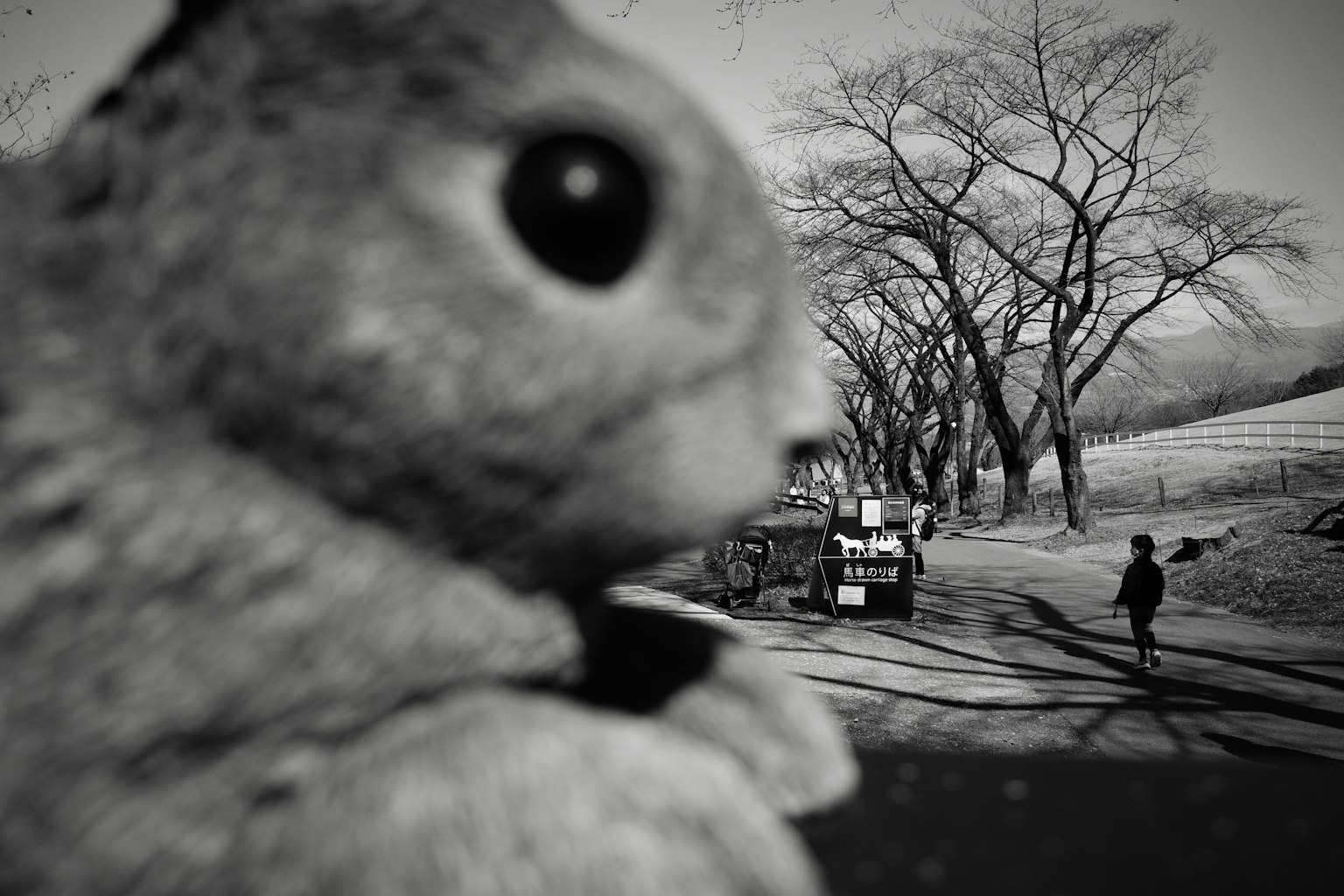 Grande figurine de lapin dans un paysage noir et blanc avec des personnes au loin