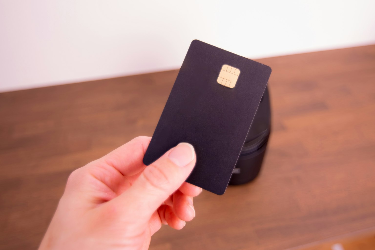 Une main tenant une carte noire avec une puce dorée
