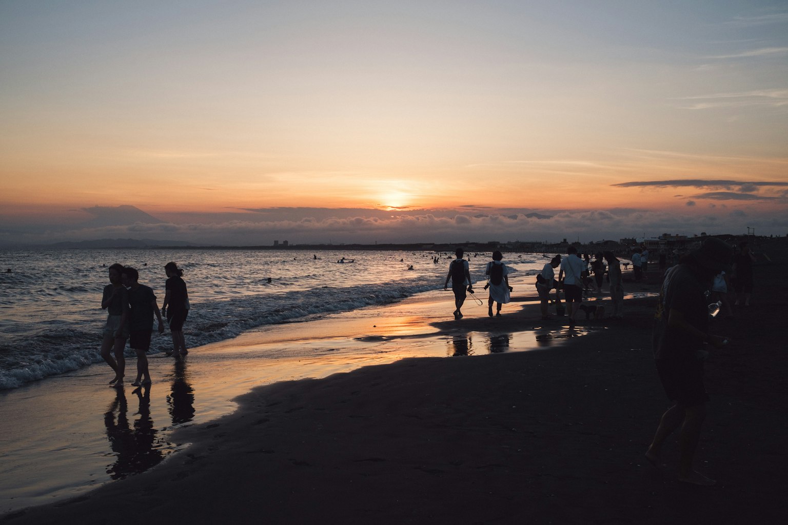 Silhouettes of people walking on the beach at sunset
