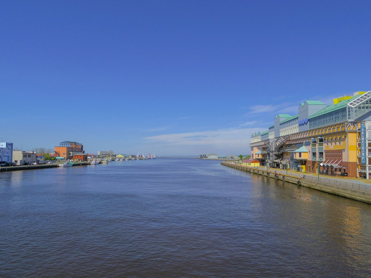Vista del fiume sotto un cielo blu chiaro con edifici colorati sulla riva