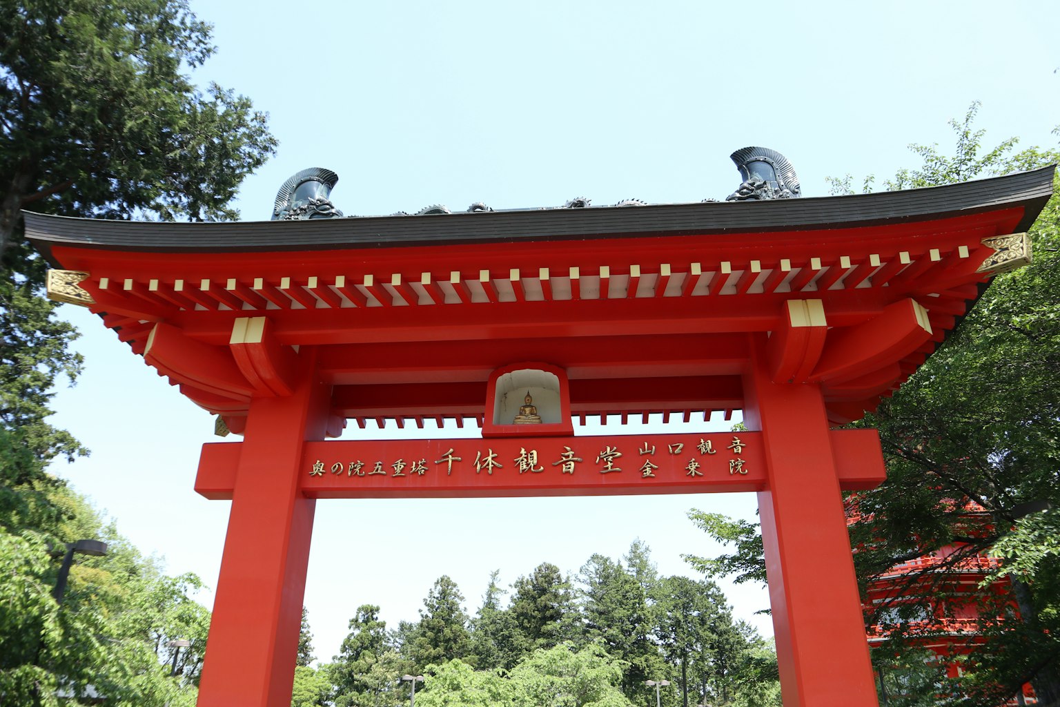 Portail torii rouge avec deux sculptures décoratives au sommet et des caractères japonais
