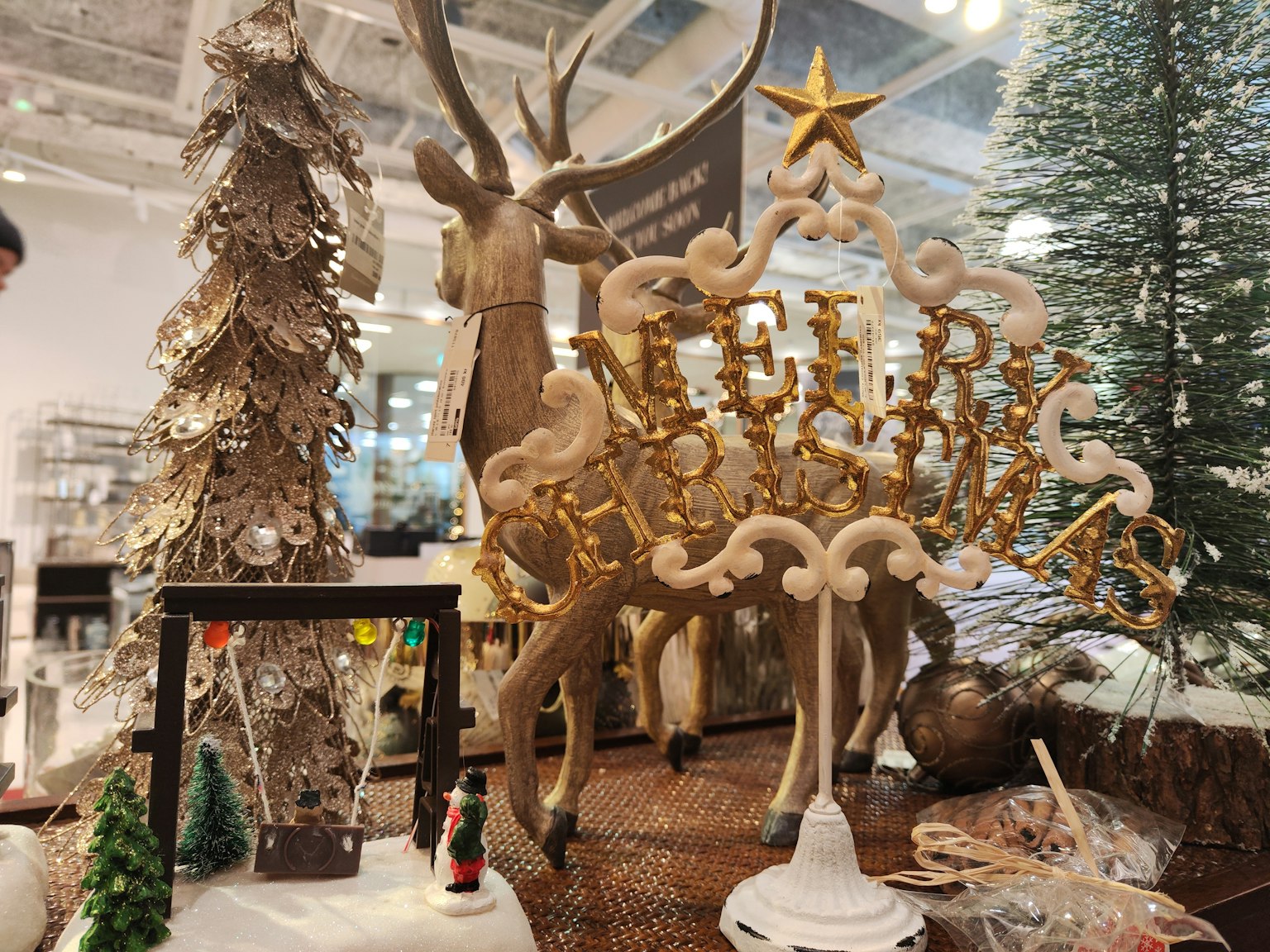 Pameran dekorasi Natal dengan tanda emas 'Selamat Natal' dan patung rusa