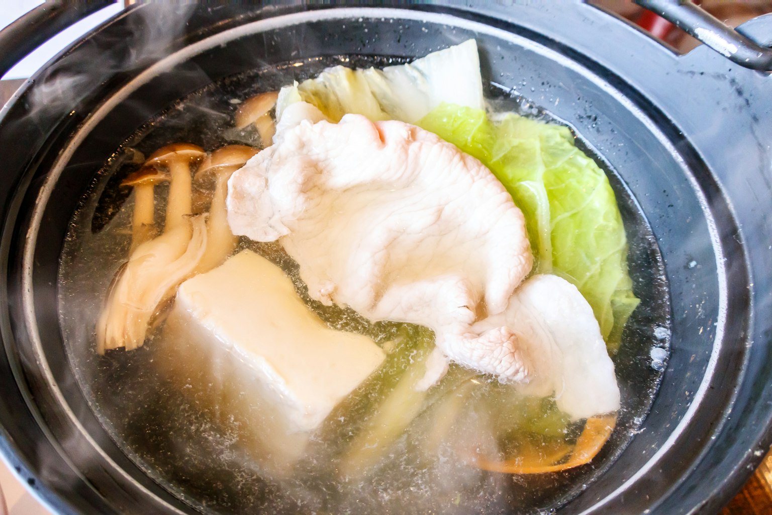 Hot pot with vegetables and tofu cooking in broth